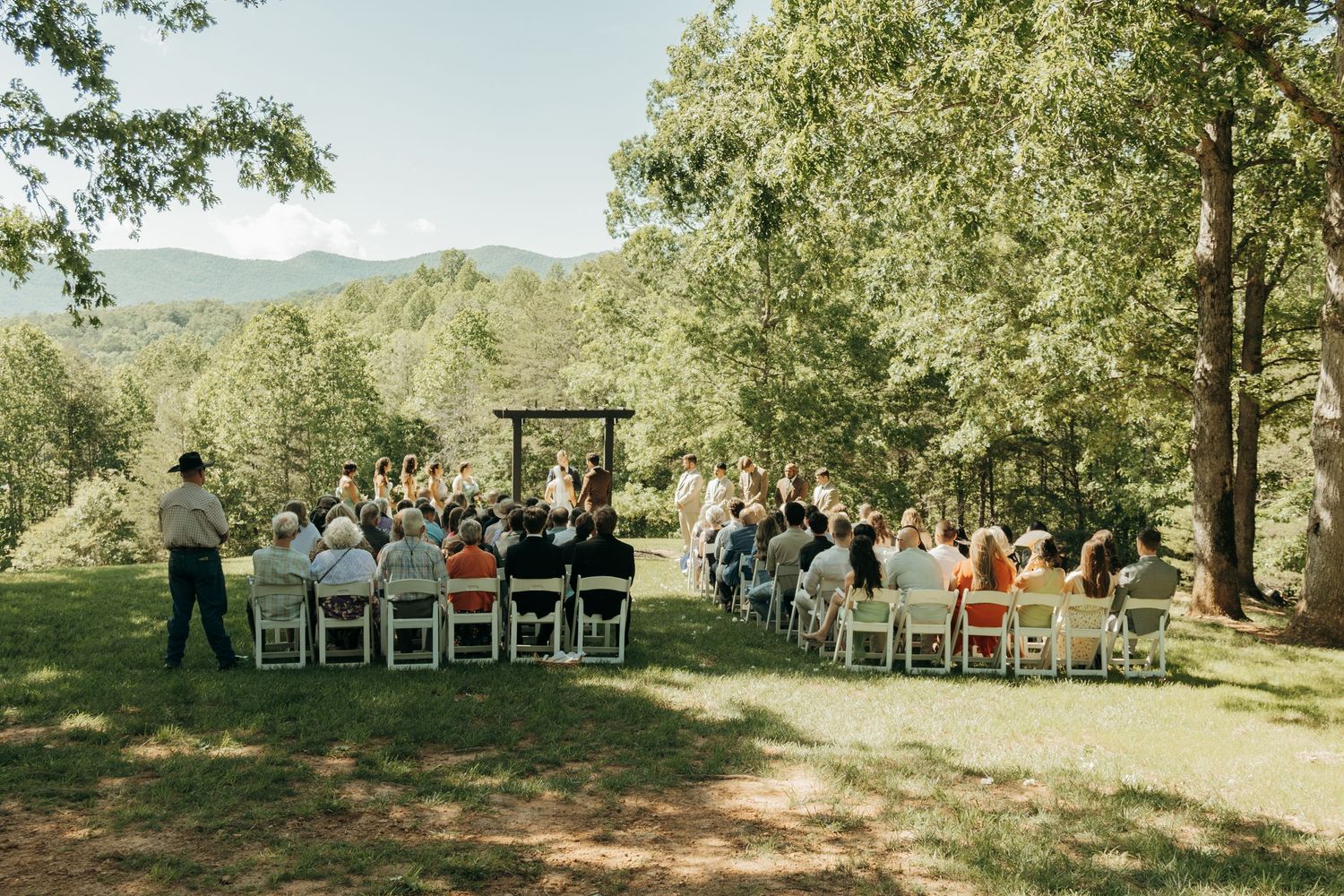 Small intimate outdoor wedding ceremony with mountain views and wooden pergola.