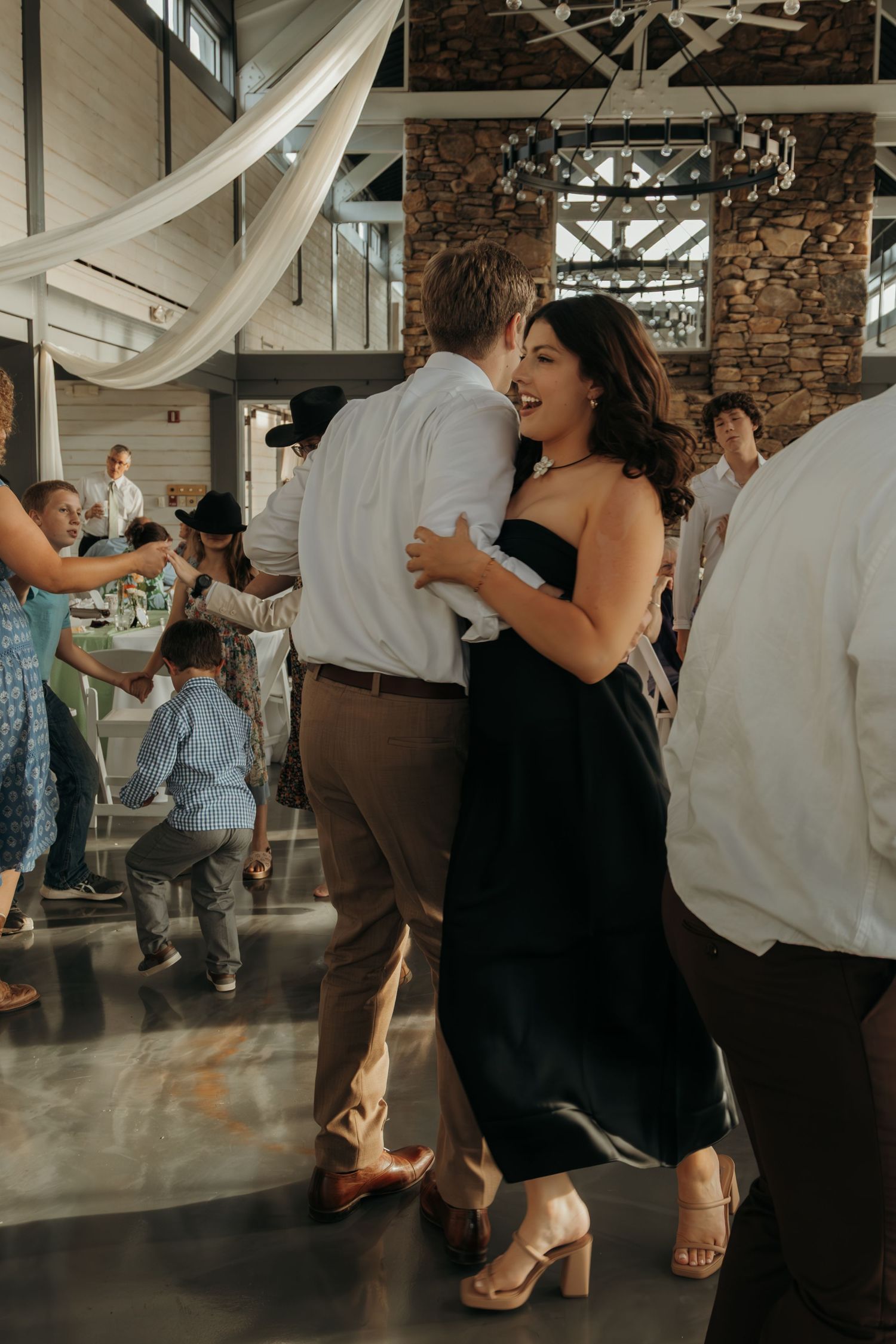 Wedding reception guests dancing and celebrating on an indoor dance floor.