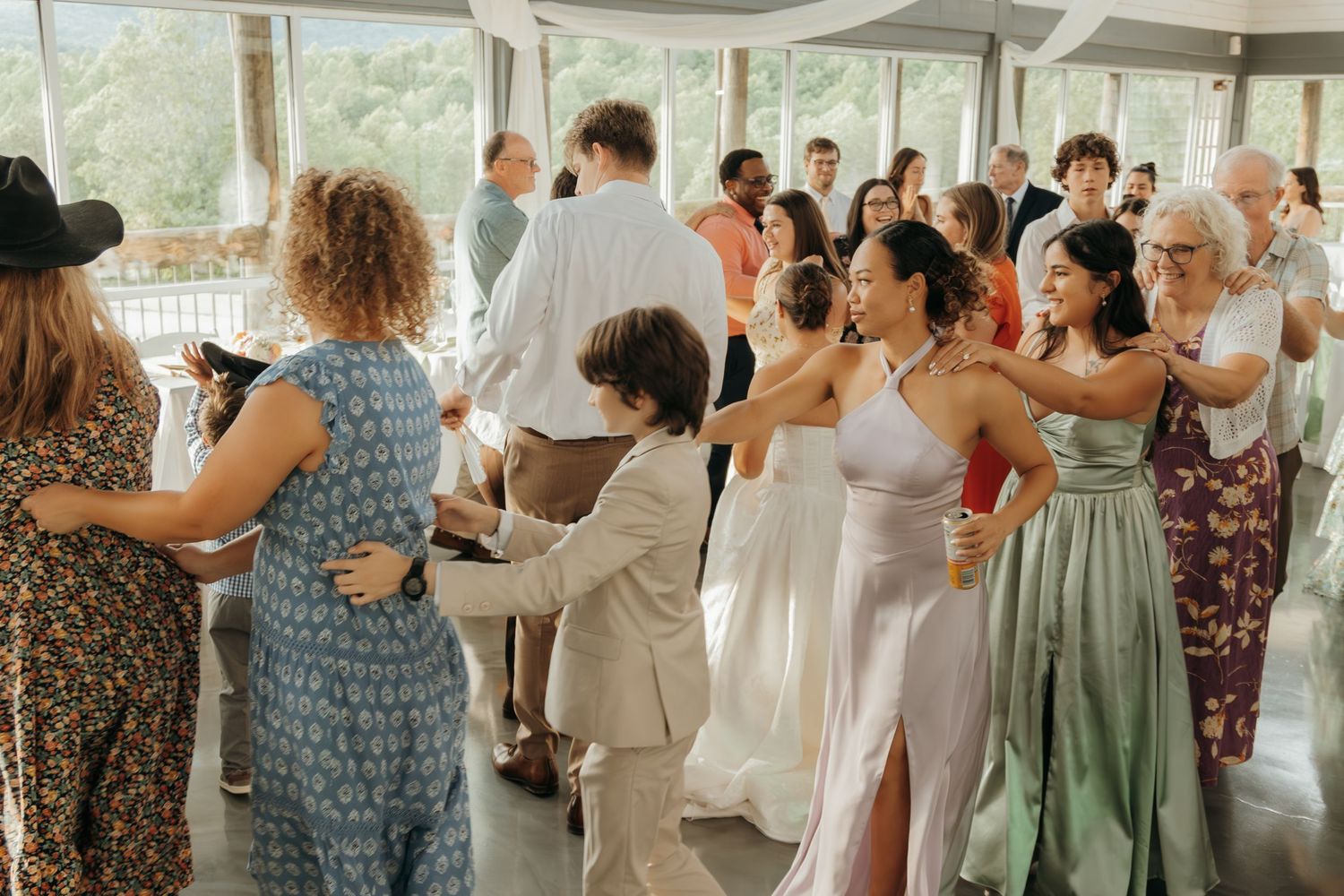 Wide shot of wedding guests enjoying themselves on a lively reception dance floor.