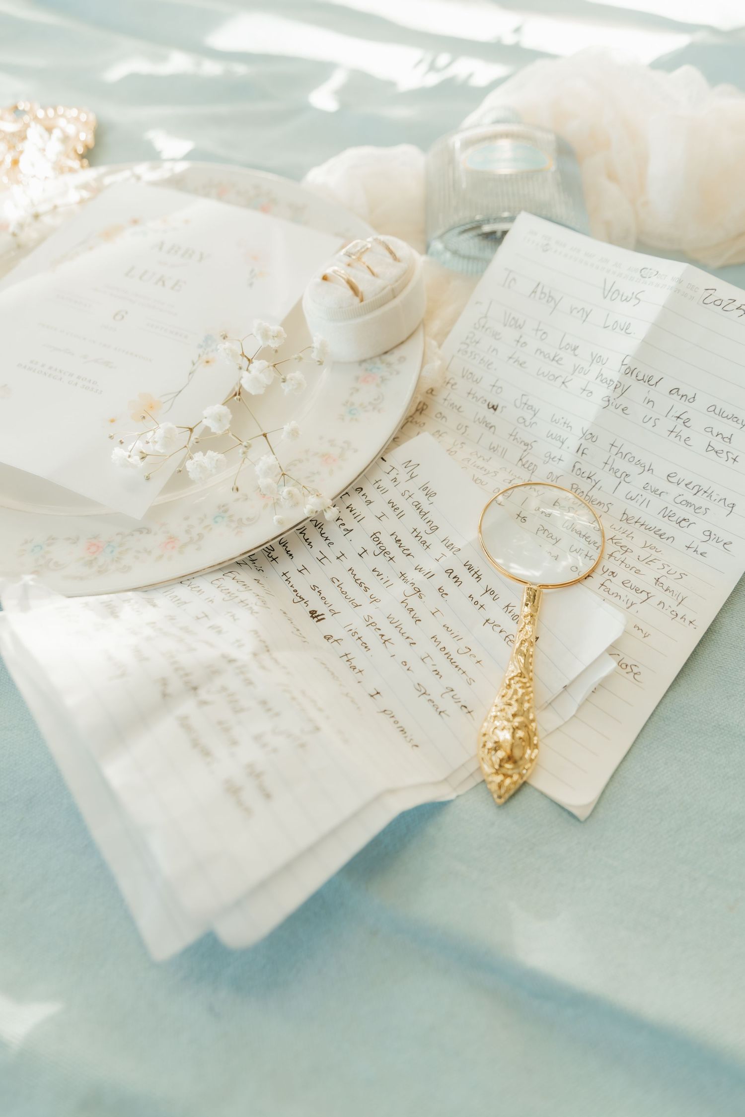 Handwritten wedding vows on delicate paper with a golden leaf accent in soft natural light.