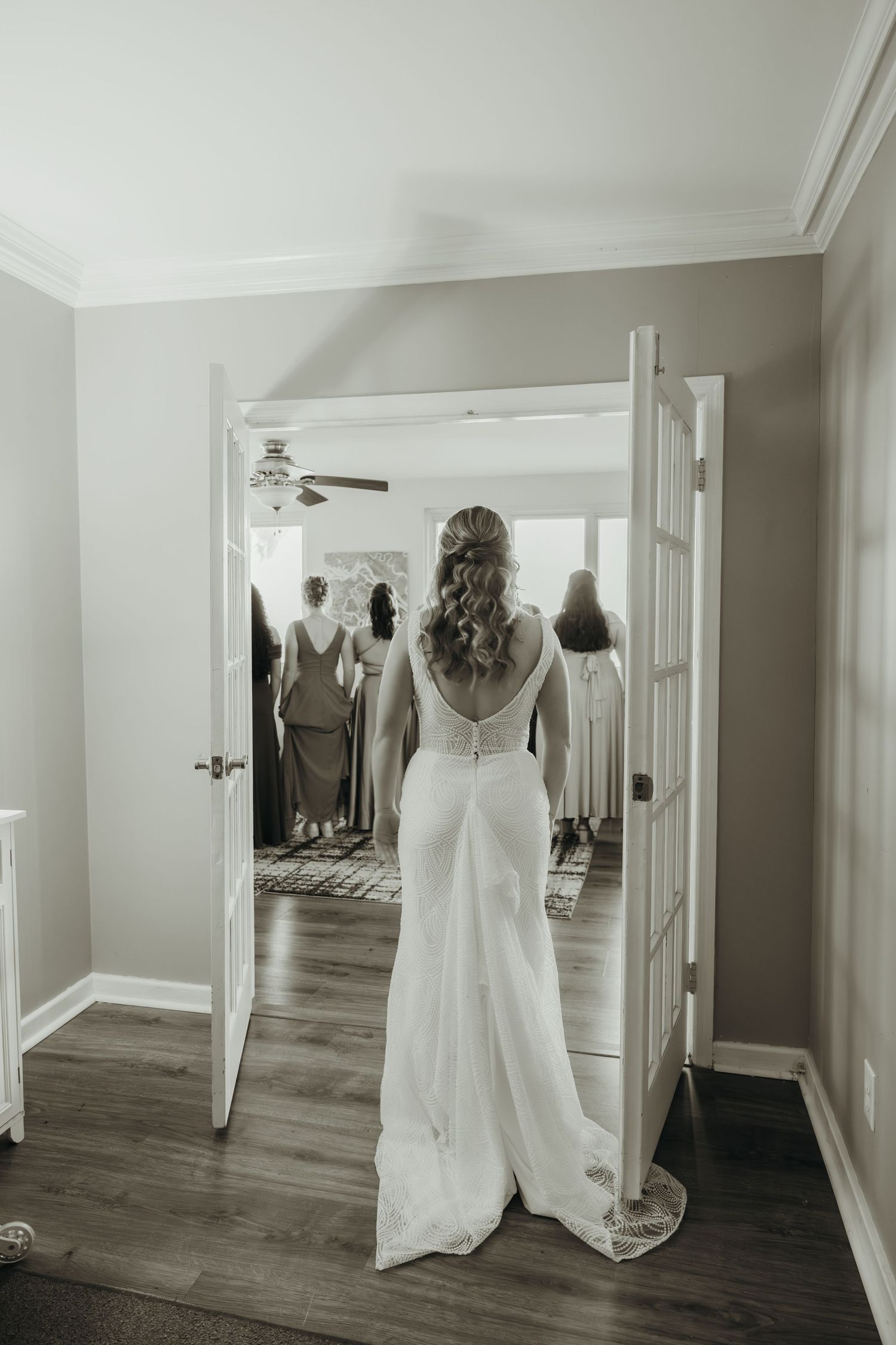 White wedding dress displayed in a hallway with mirrors and hardwood floors.
