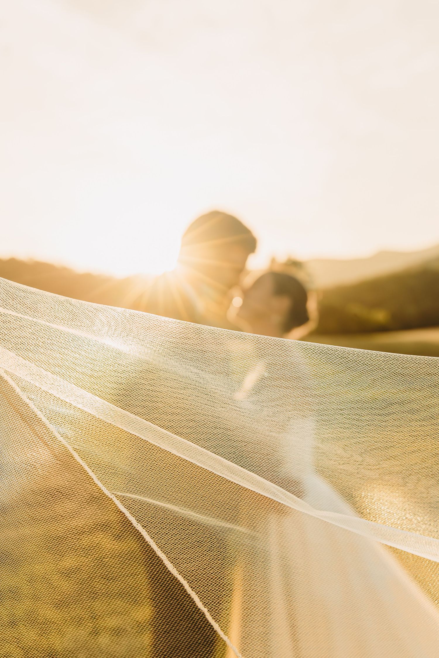 A romantic sunset photo through wedding veil texture with mountains in background.