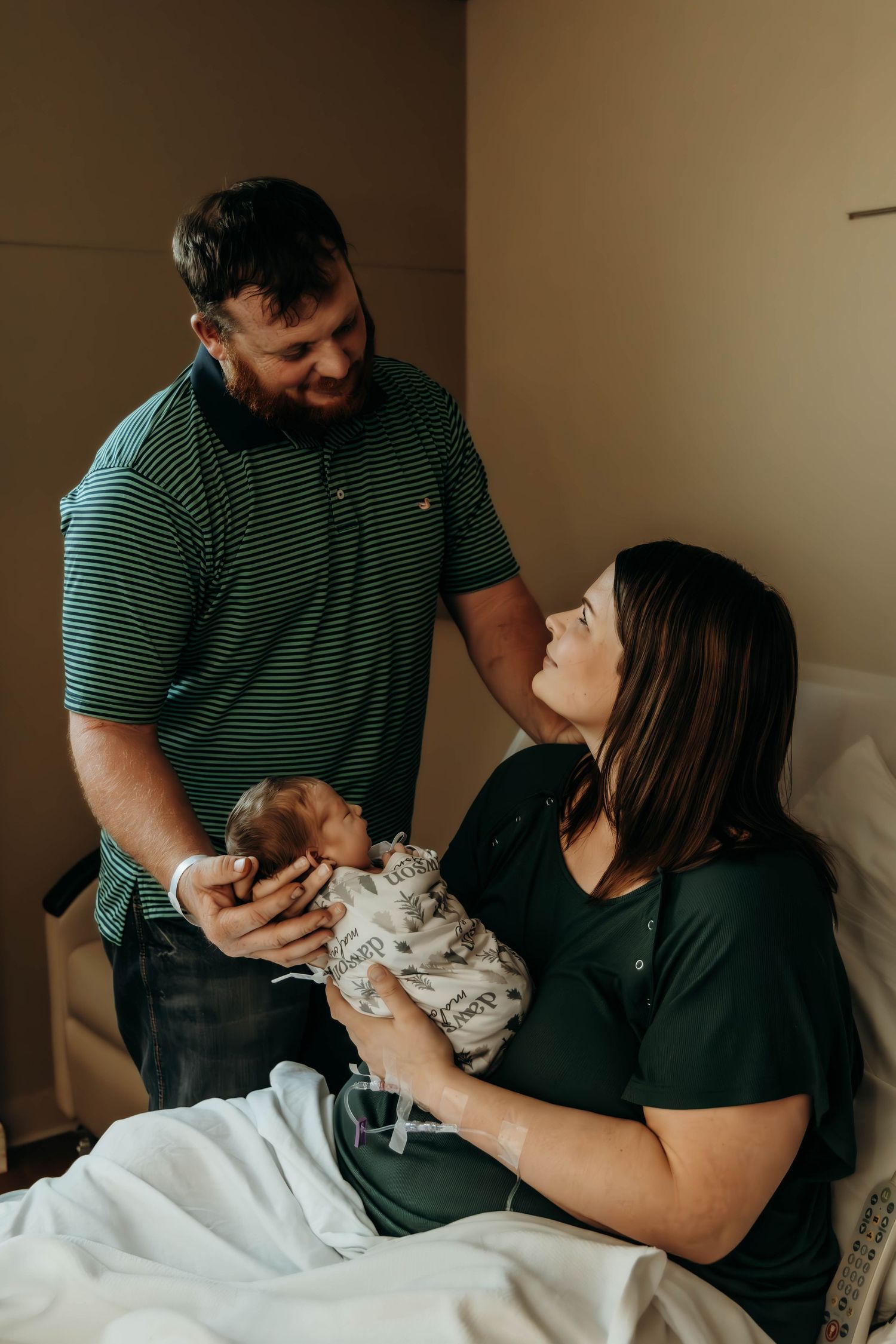 Family sharing tender moment with newborn baby in hospital room together.