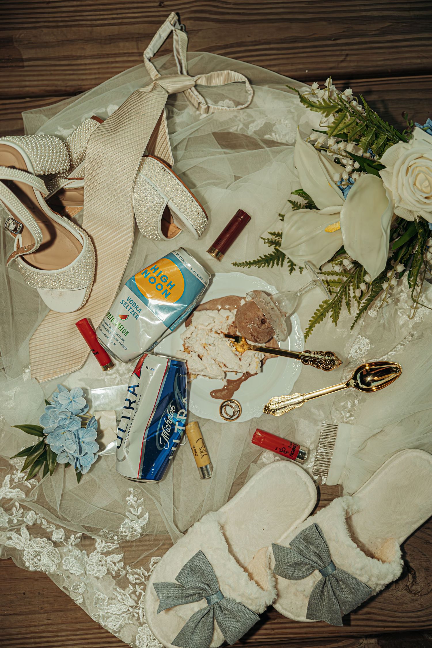 Wedding details and accessories including flowers, ribbons, and personal items arranged on wooden surface.