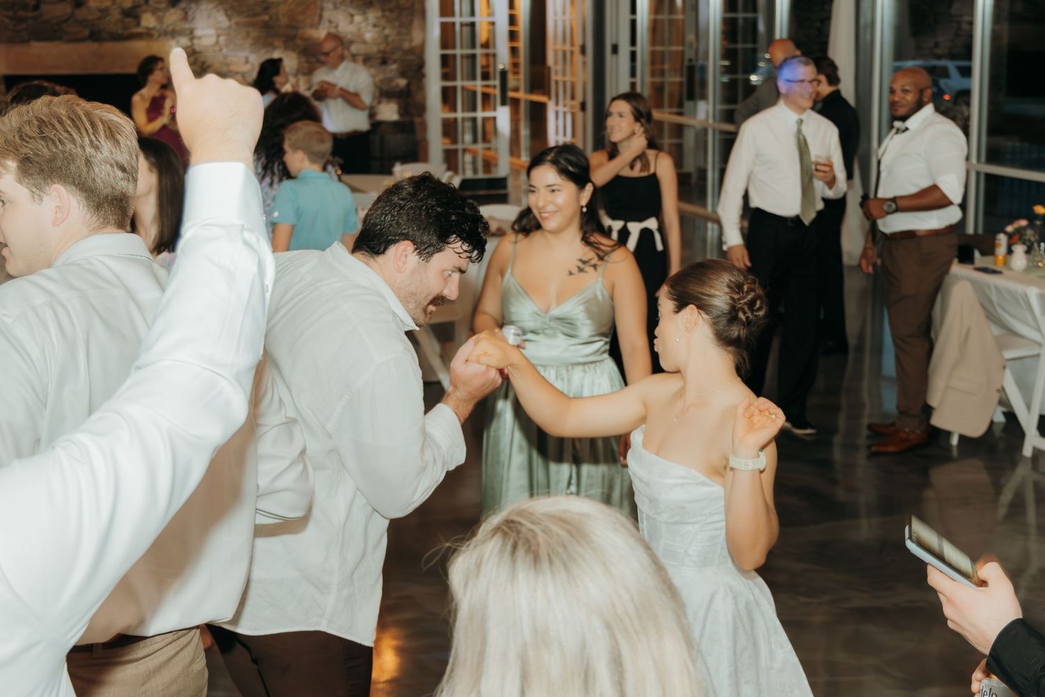 Festive wedding reception dance floor with guests celebrating under decorative white draping.