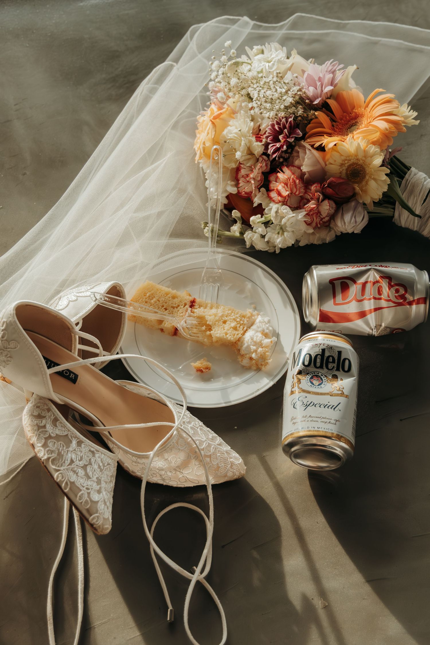 Bridal accessories with lace shoes, floral bouquet and refreshments on textured background.