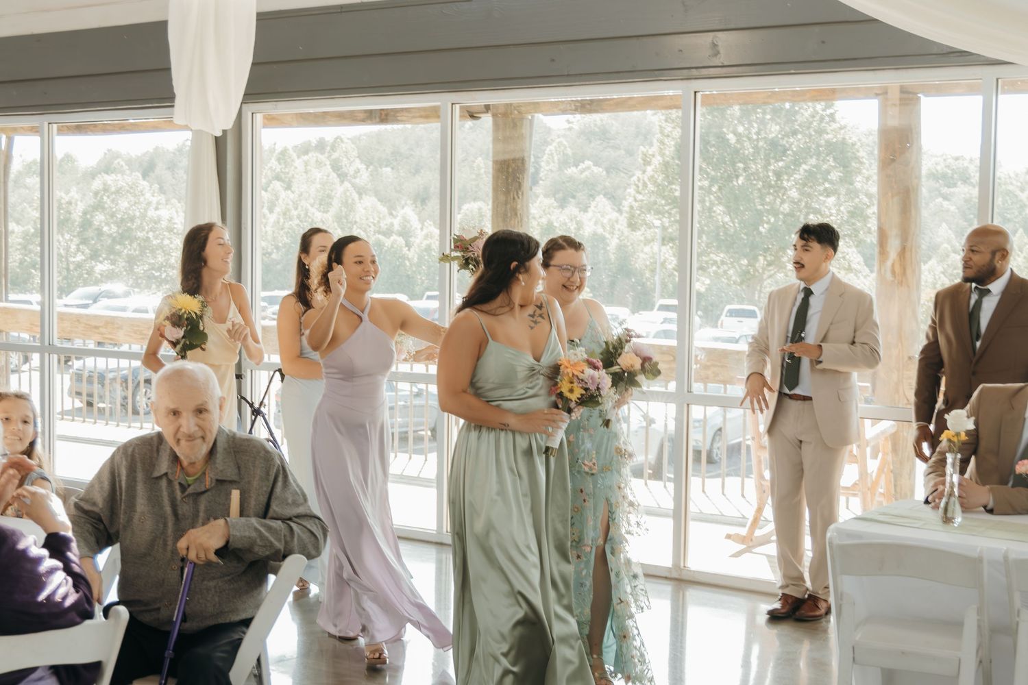 Wedding reception guests celebrate and dance in a bright indoor venue with mountain views.