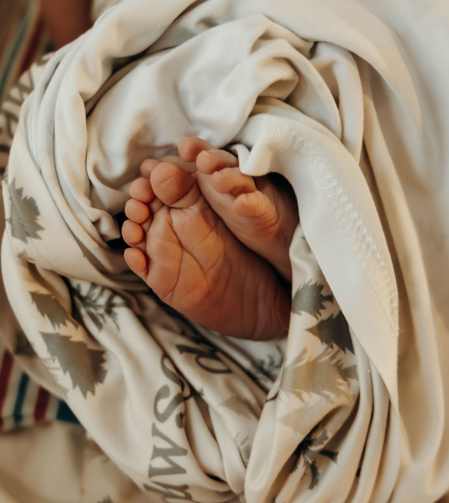 Newborn baby hands wrapped in soft beige blankets with text visible in a collage-style layout.