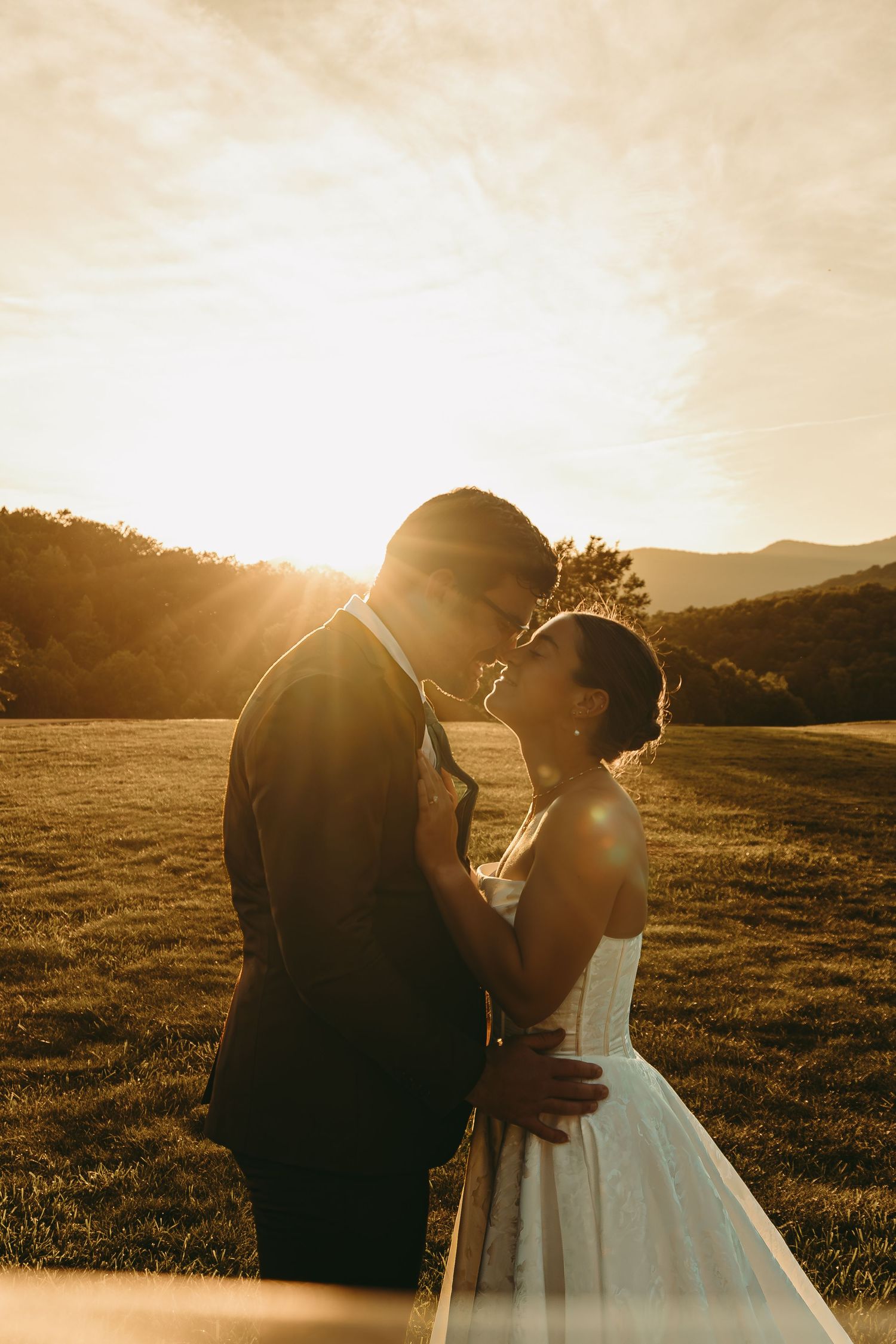 A romantic silhouette of a wedding couple embracing in golden sunset light.