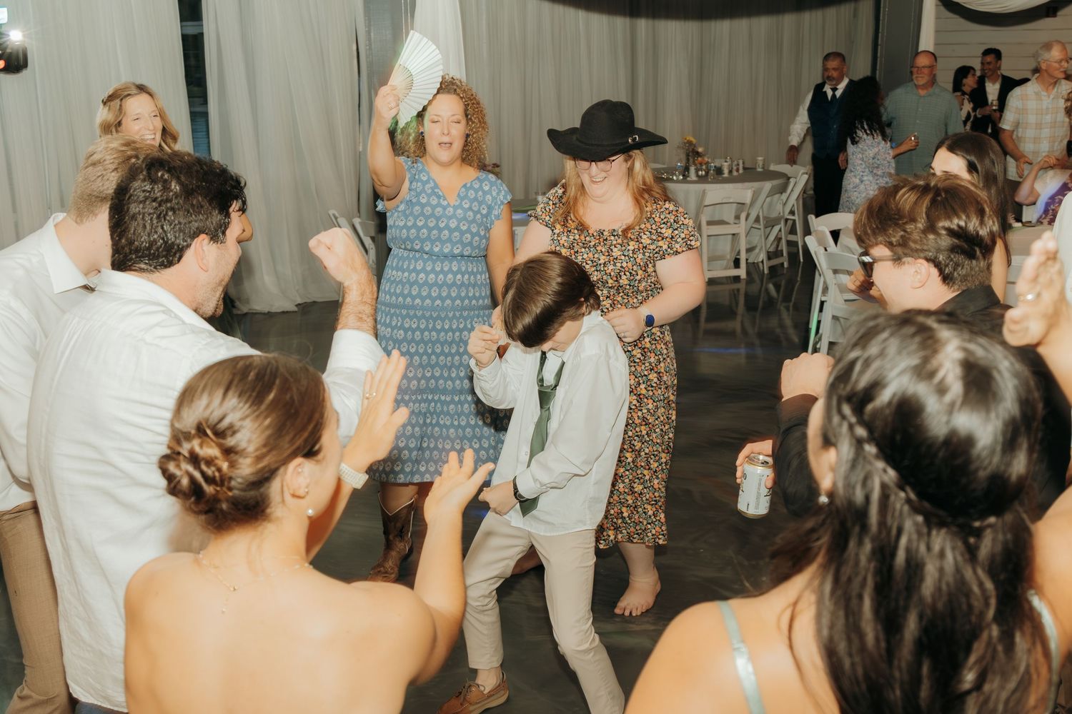 Wedding celebration with dancers enjoying themselves under draped fabric decor in an indoor venue.
