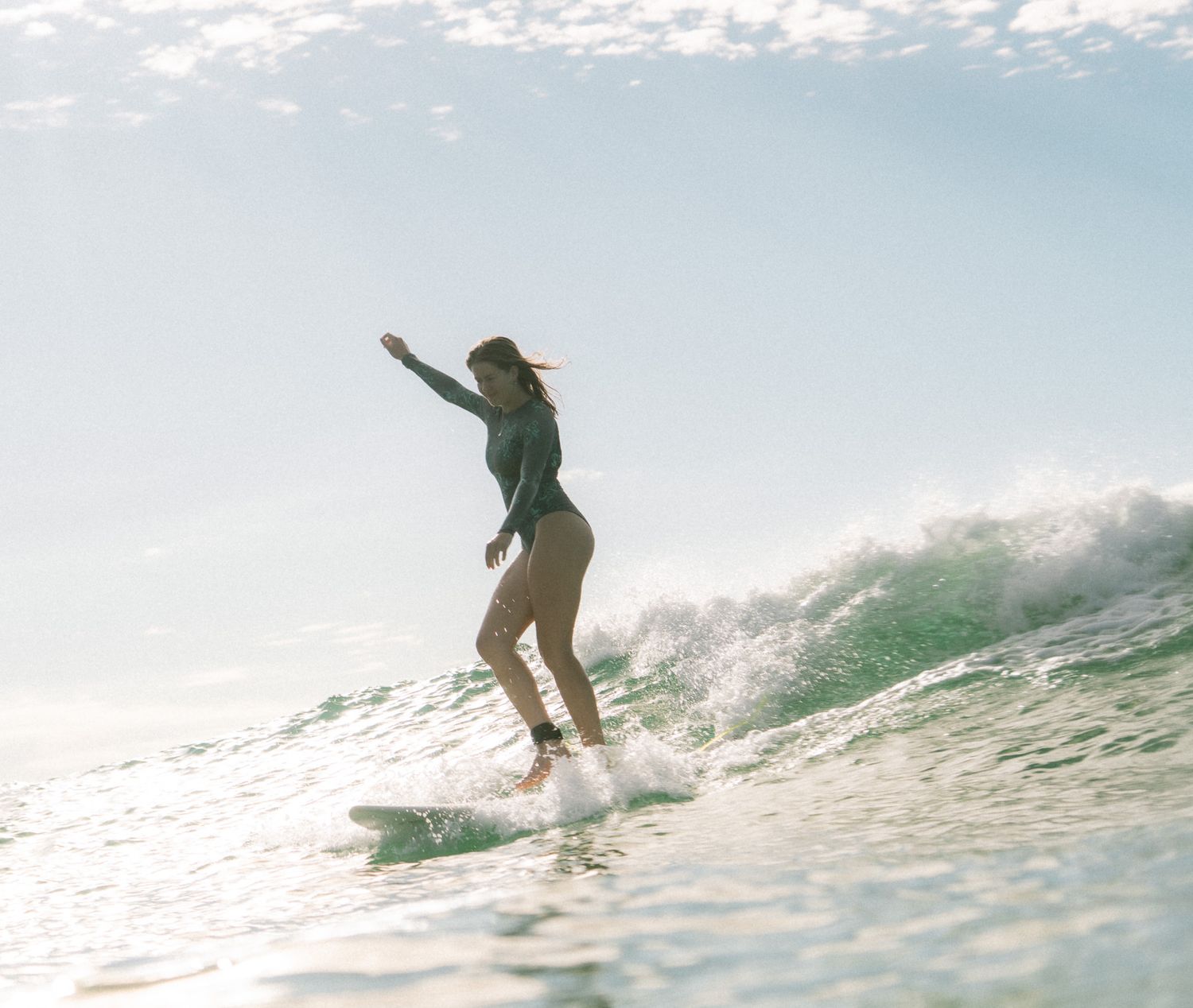 Girl angelically cross stepping on a mid-length surfboard on a group social surf with Sunlight Surfers Dudley Newcastle NSW