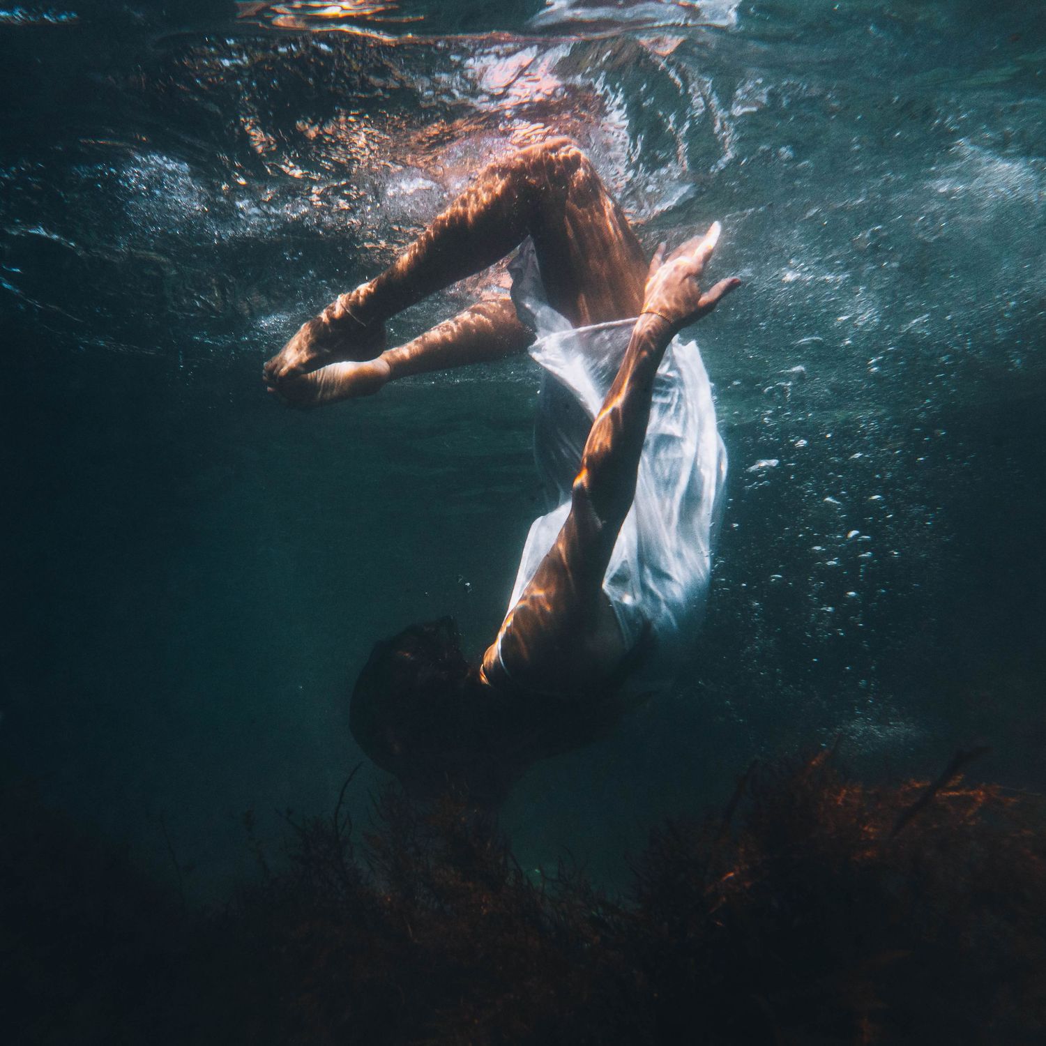 portrait of a girl in white underwater in the ocean rockpool with beautiful morning light reflecting on her skin in Mid North Coast NSW