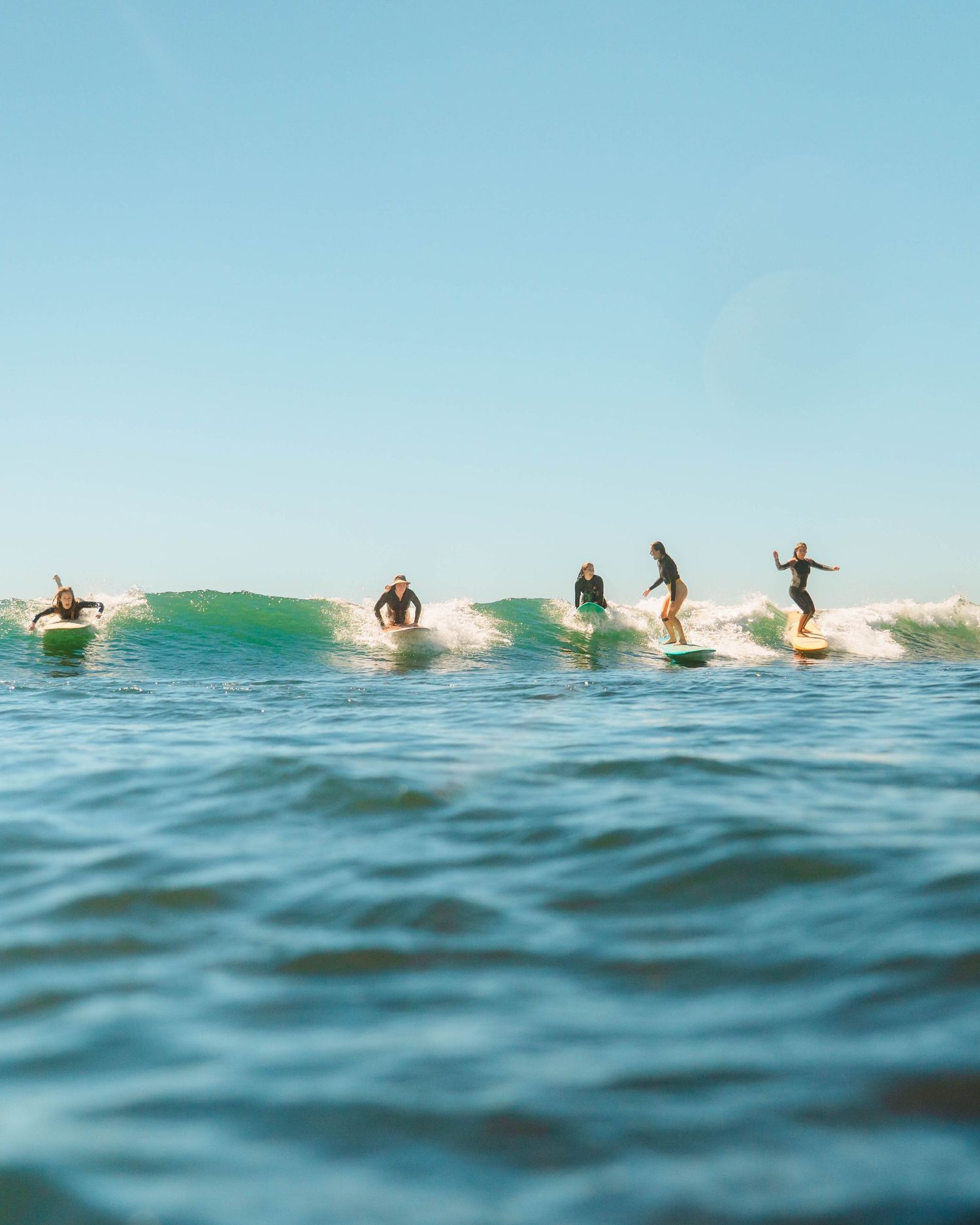 five women surfers on longboards having fun on a part wave together at crescent head NSW mid north coast with Sunlight surfers camp out
