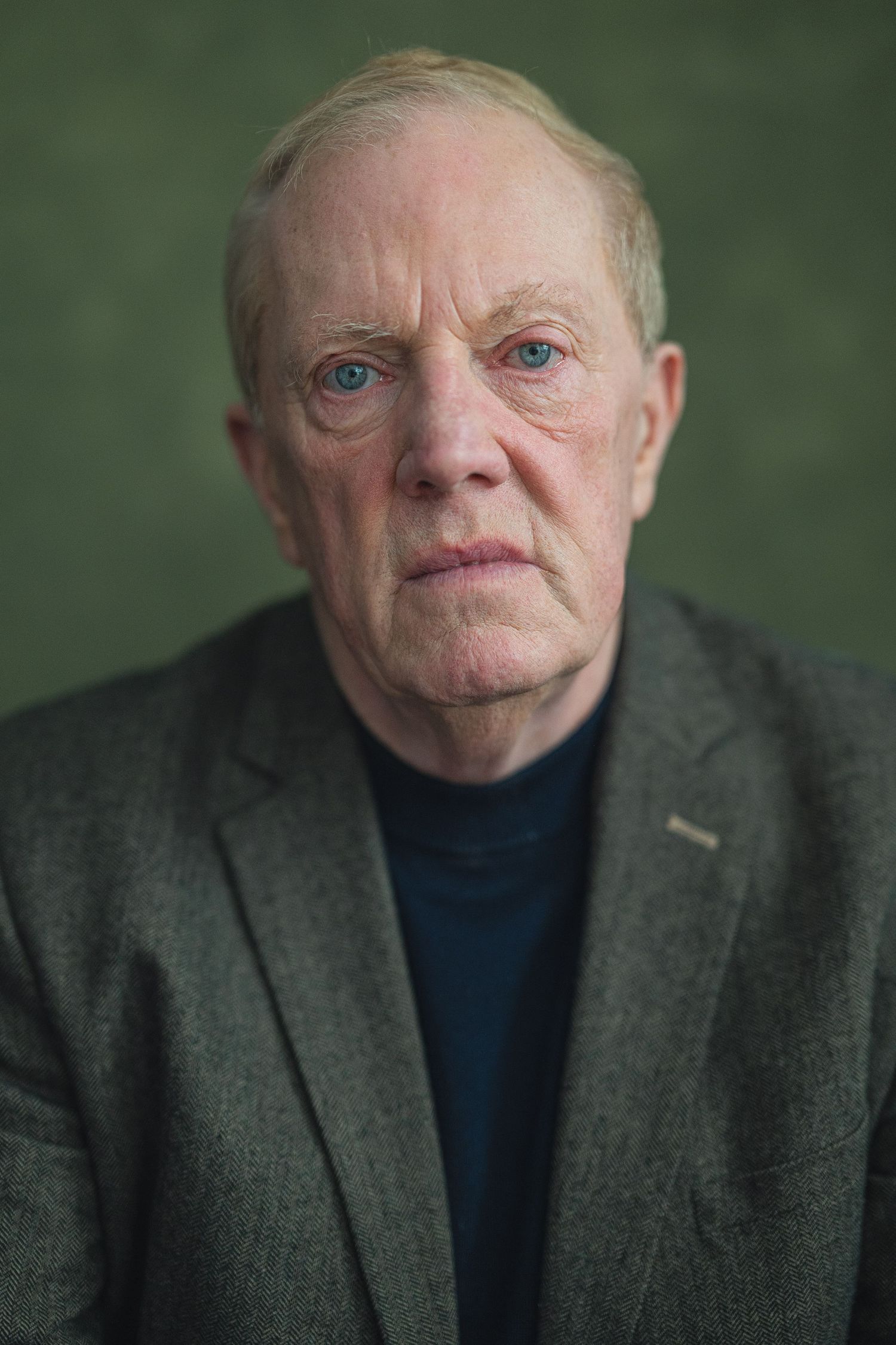Portrait series showing close-up facial expressions in a gray suit jacket against a green background.