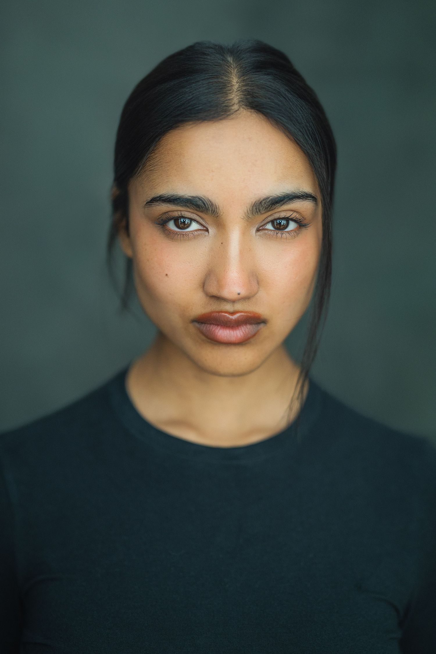 Portrait series with dramatic lighting against a dark green background showcasing different facial expressions and angles.