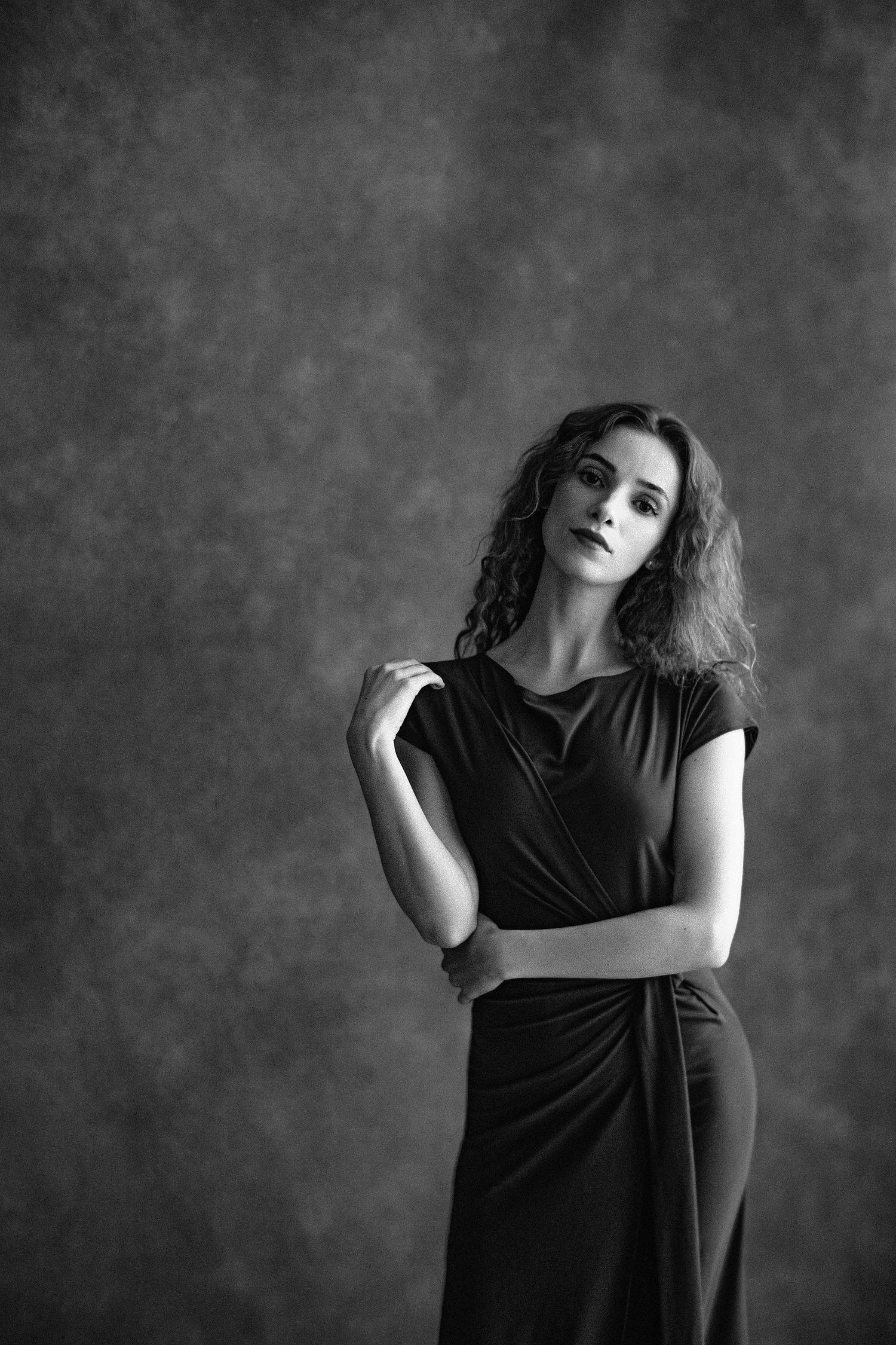 A dramatic black and white photo series showing a person in a black dress posing expressively against a dark background.