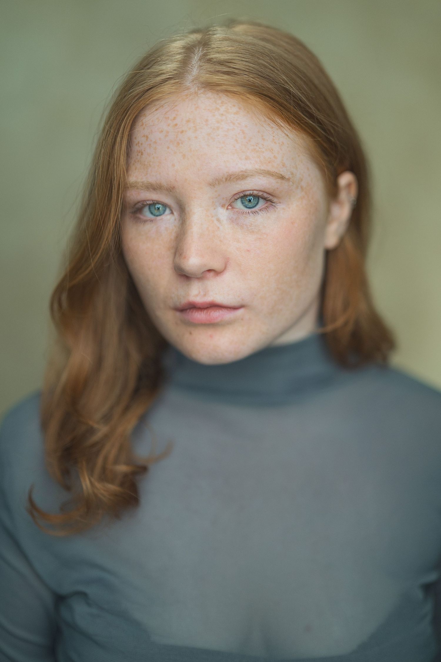 A portrait series showing different angles of a person with red hair wearing a gray turtleneck sweater against a neutral background.