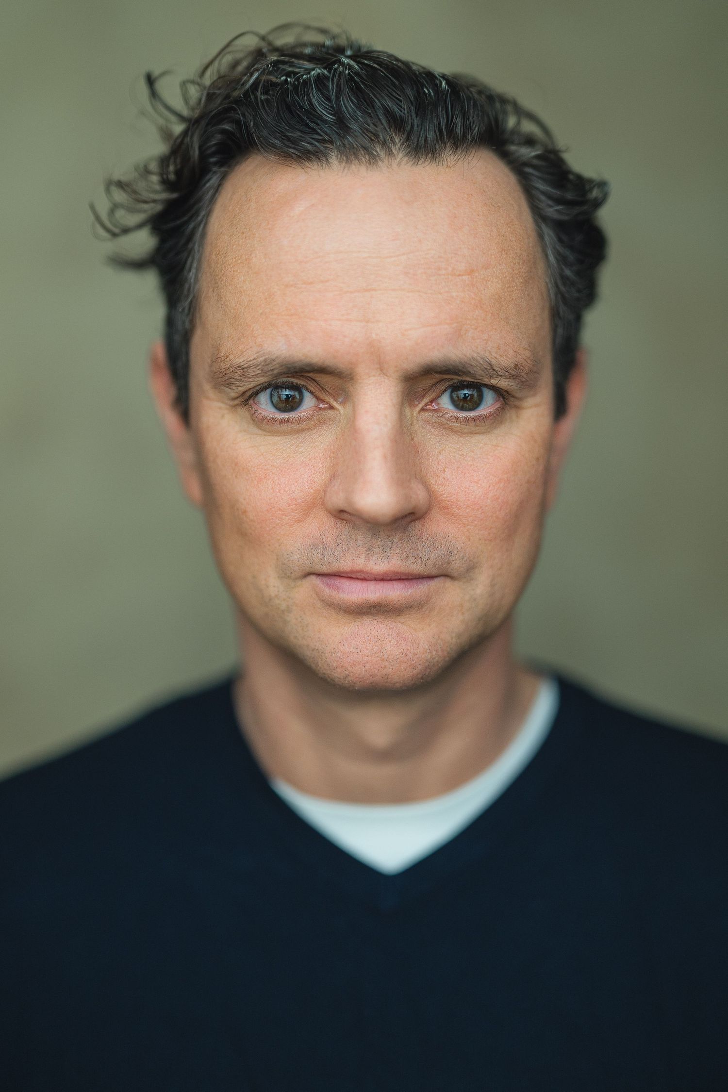 Portrait series showing a person in a dark shirt against a muted green background with varying facial expressions.