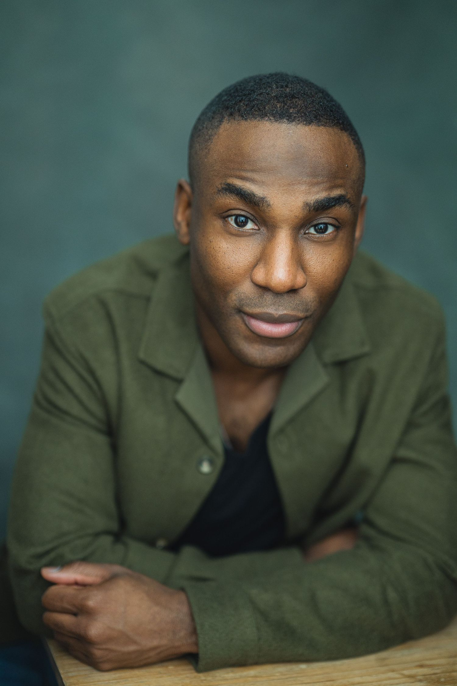 Professional headshot series showing warm expressions while wearing an olive green jacket against a teal background.