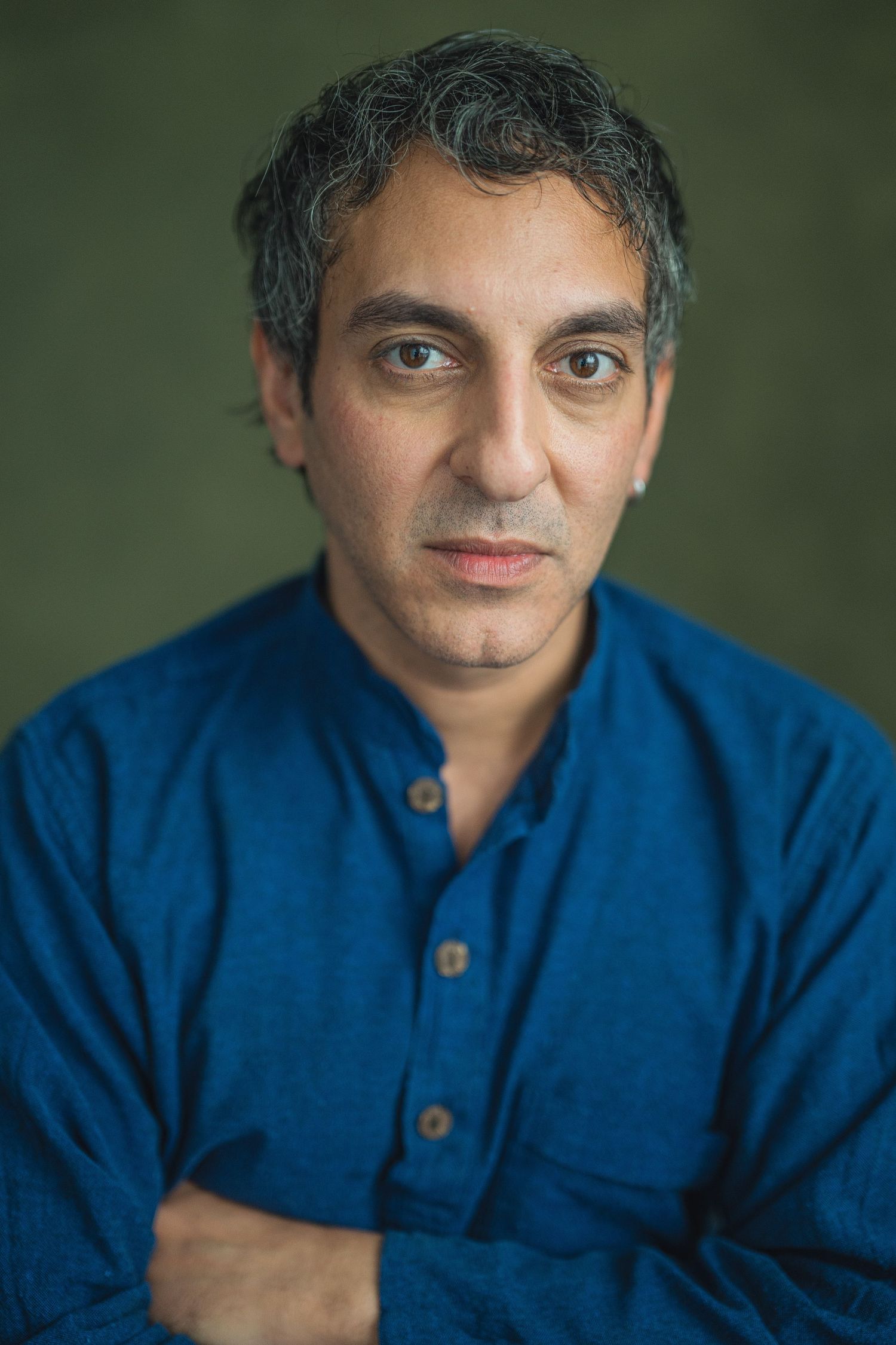 A series of headshots showing someone wearing a dark blue button-up shirt against a green background.