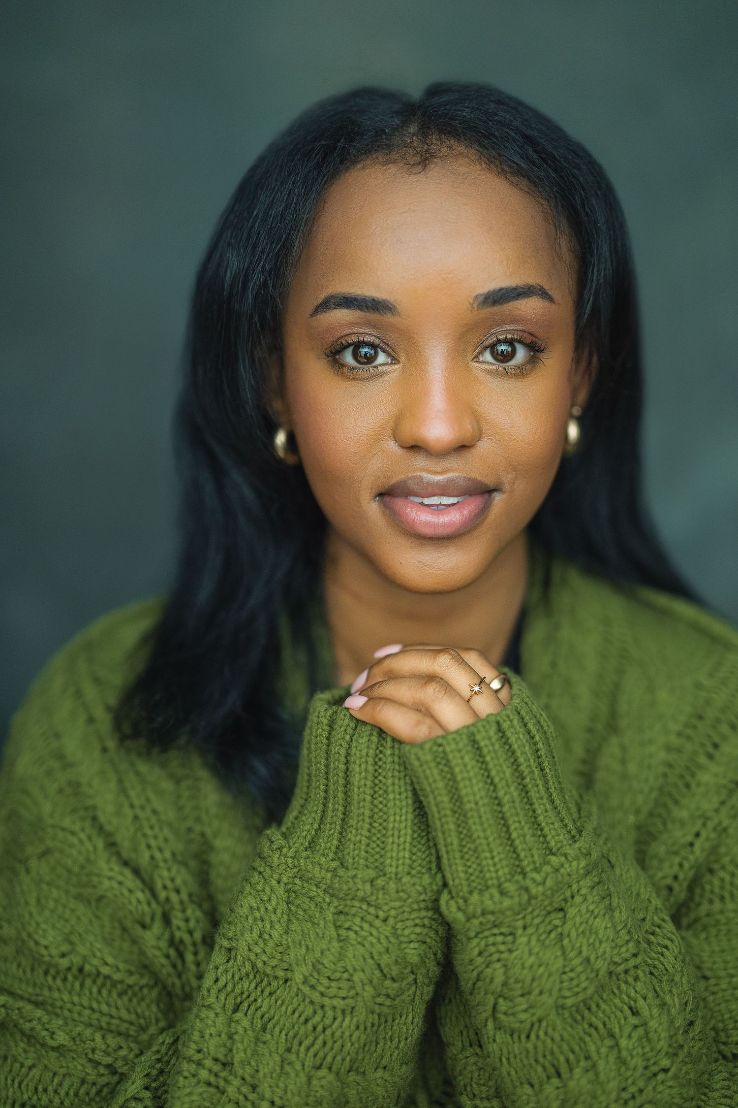 A portrait series showing someone wearing a cozy green cable knit sweater against a dark background.