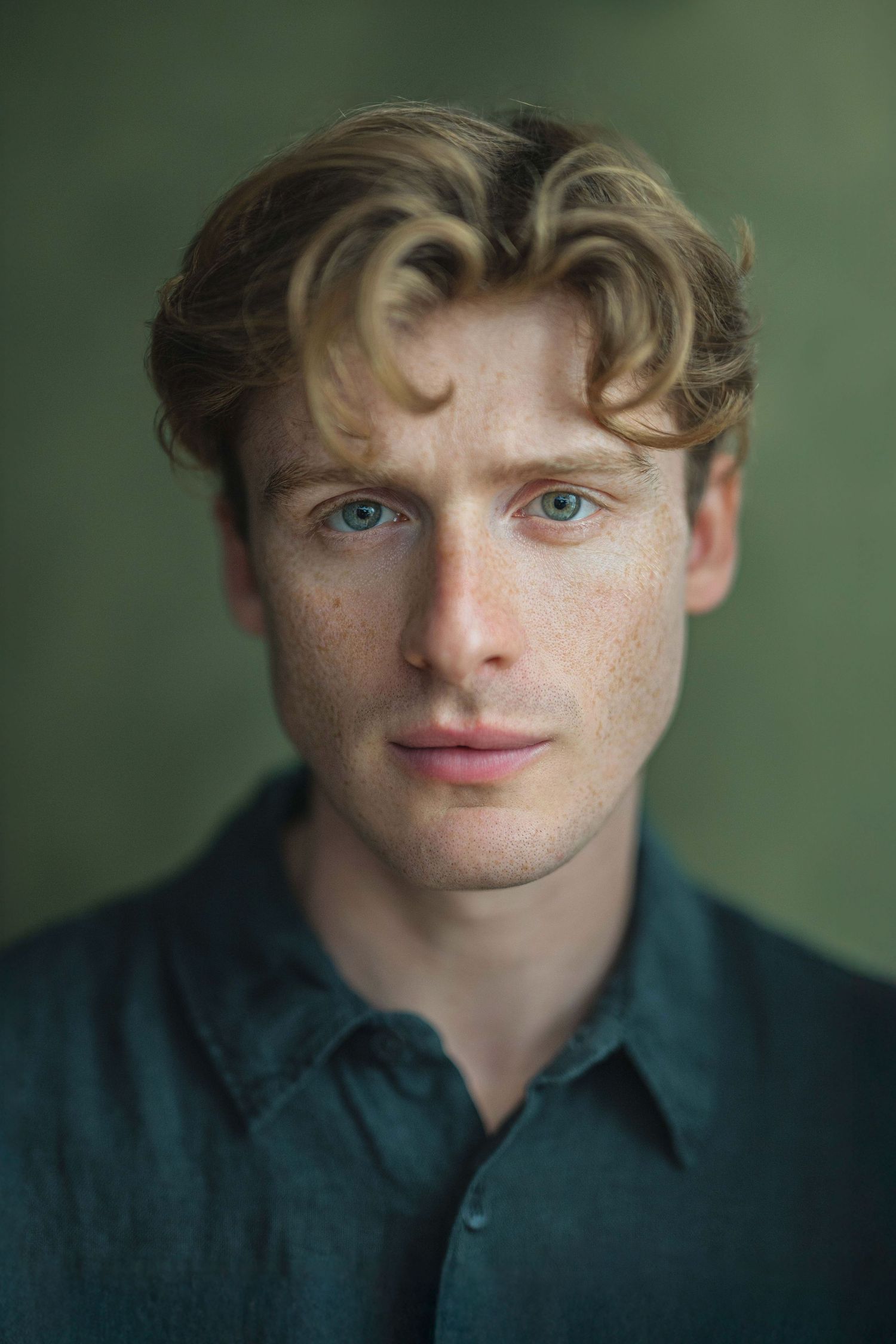 Close-up portrait series showing freckled features and blue eyes against a dark green background.