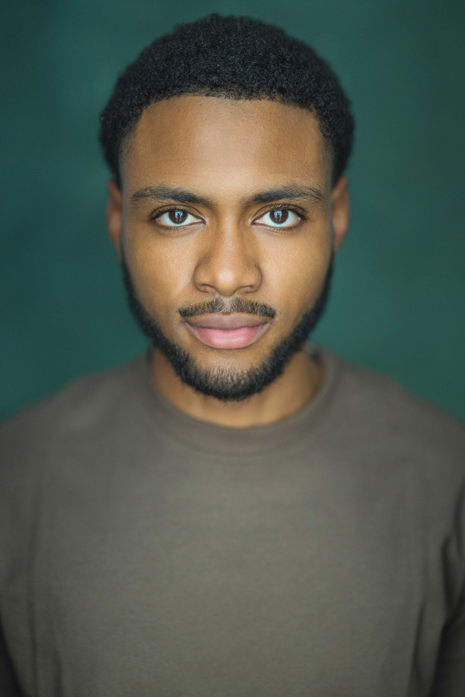 Professional headshot portrait against a dark green background with soft lighting and shallow depth of field.