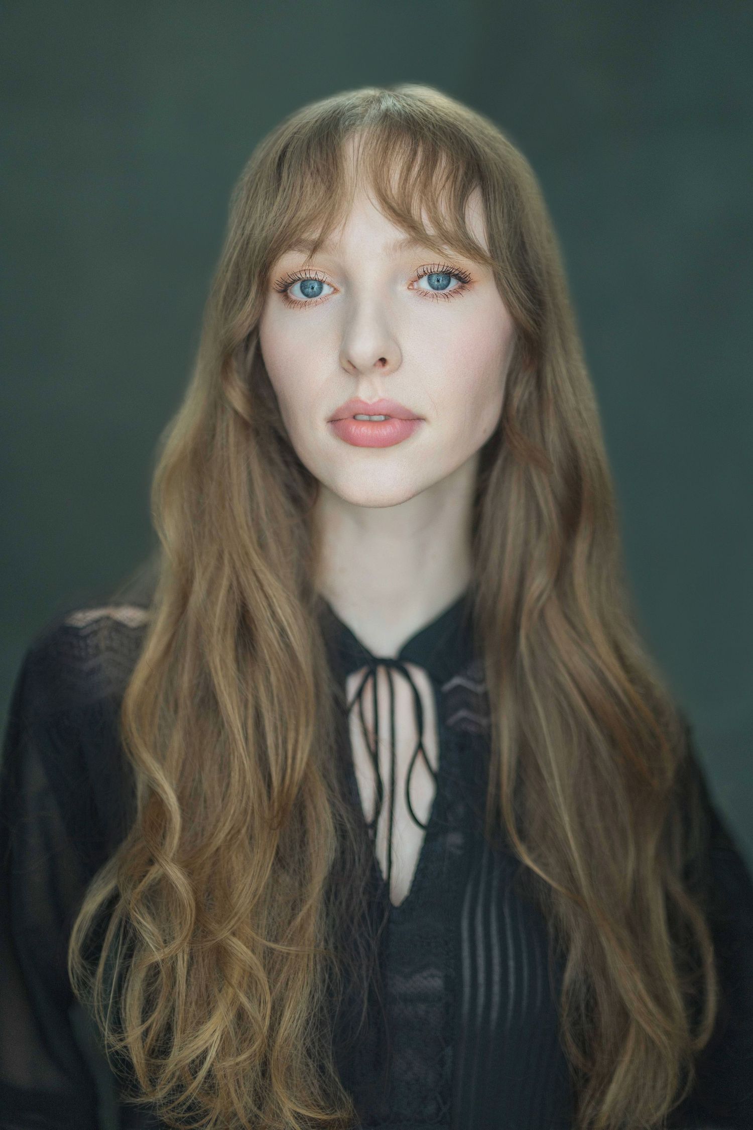 A series of five portraits showing someone with long wavy hair and bangs wearing a black top with a white collar.