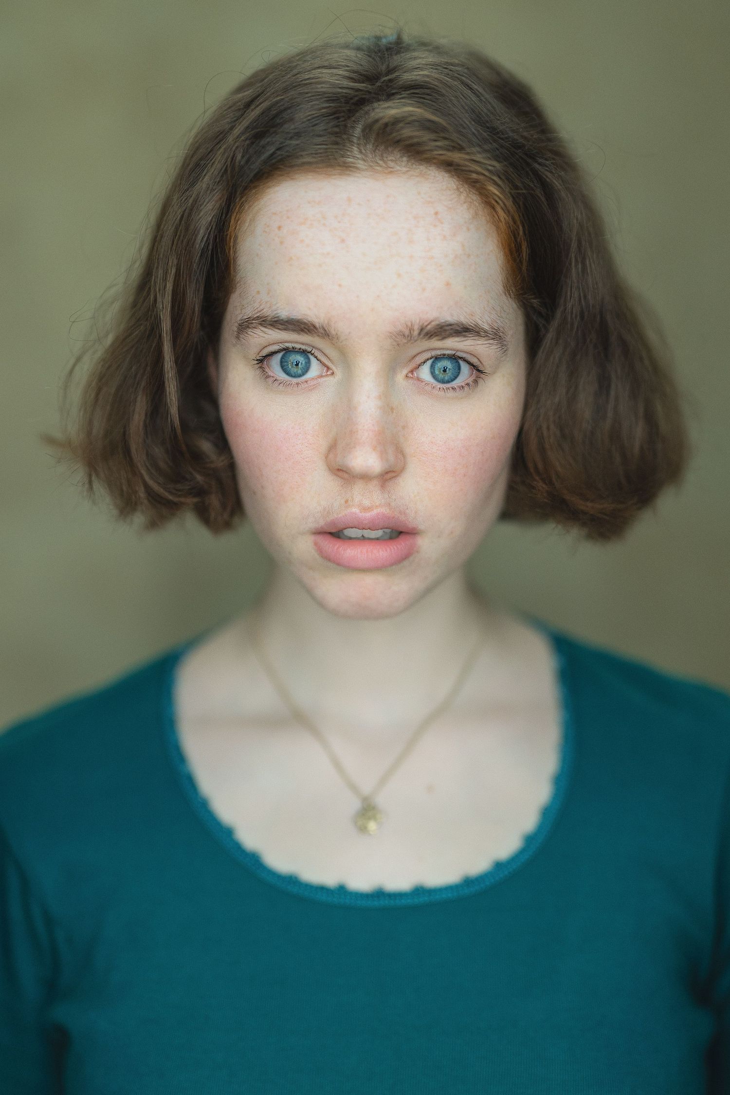 Five portrait photos show striking bright blue eyes and brown hair against a teal shirt and muted background.