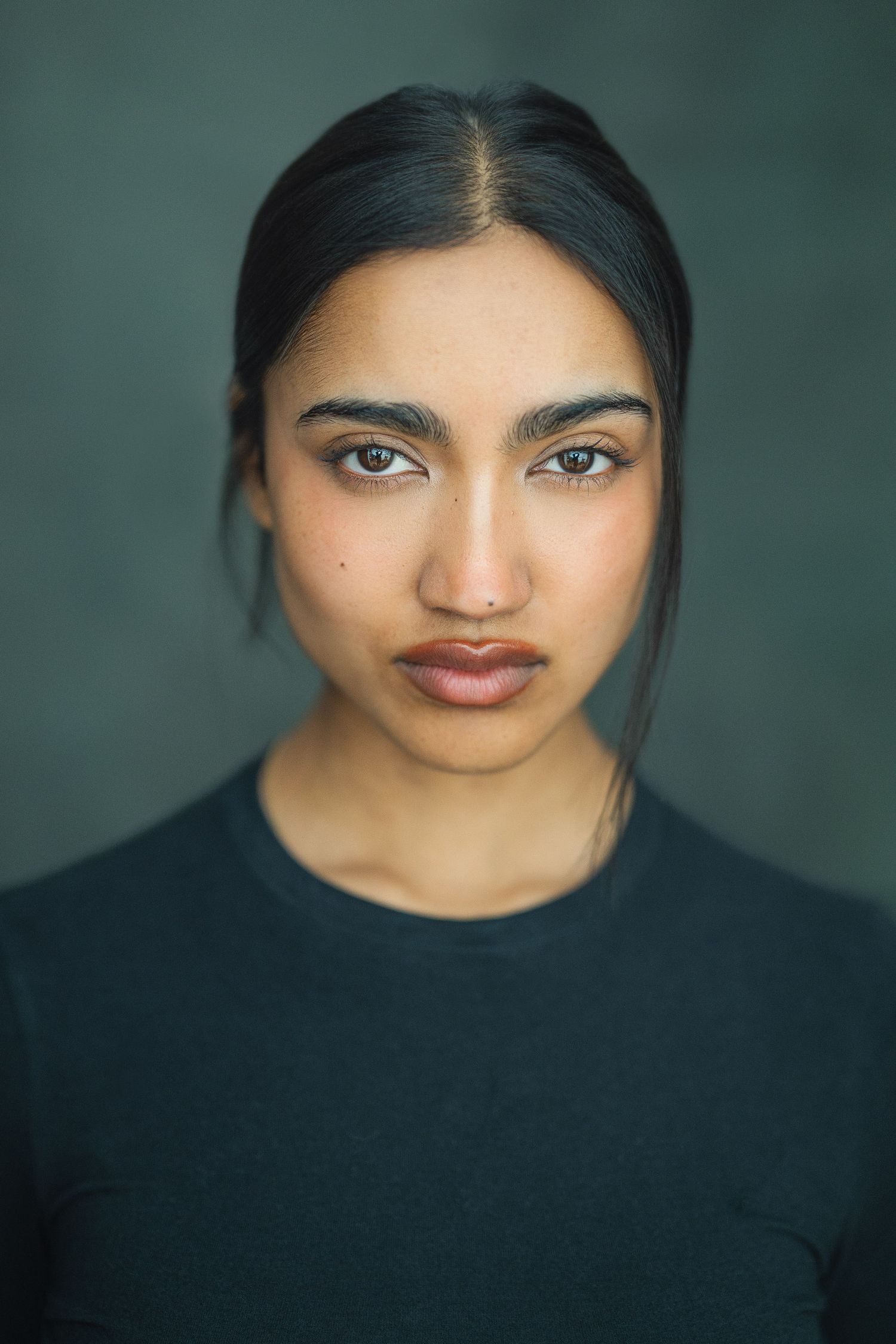 Portrait series showing close-up views against dark background wearing black top with dramatic lighting.