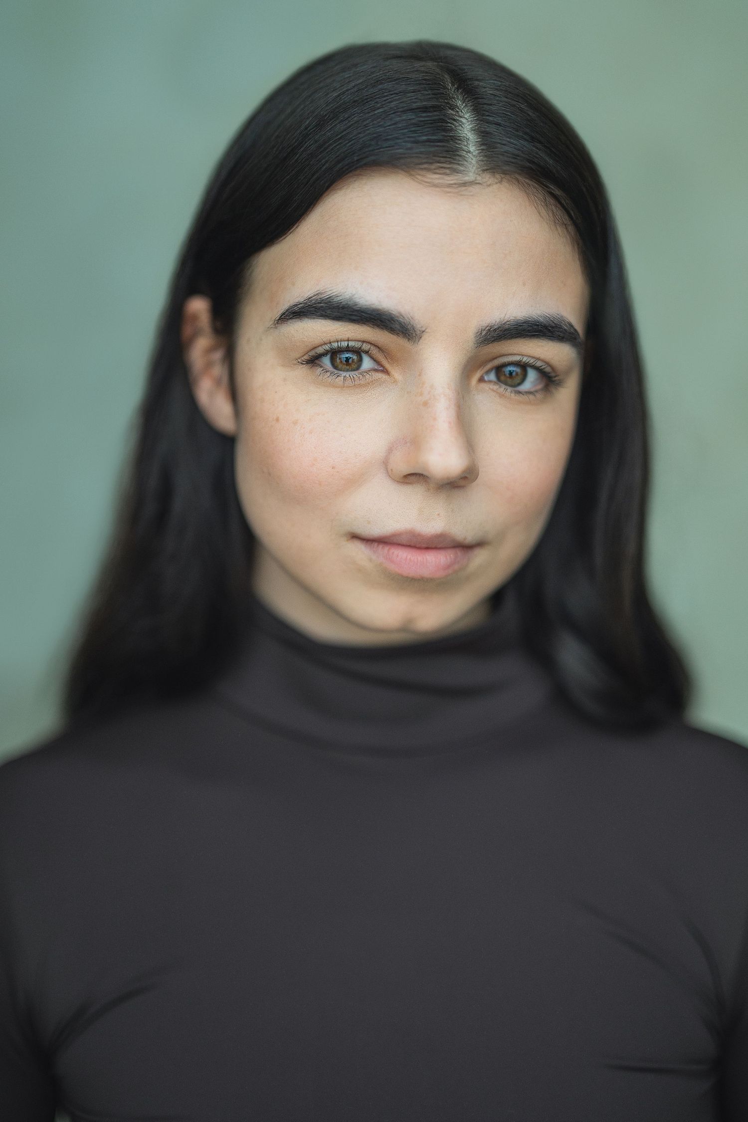 Portrait series showing a figure with long dark hair and black turtleneck against a mint green background.