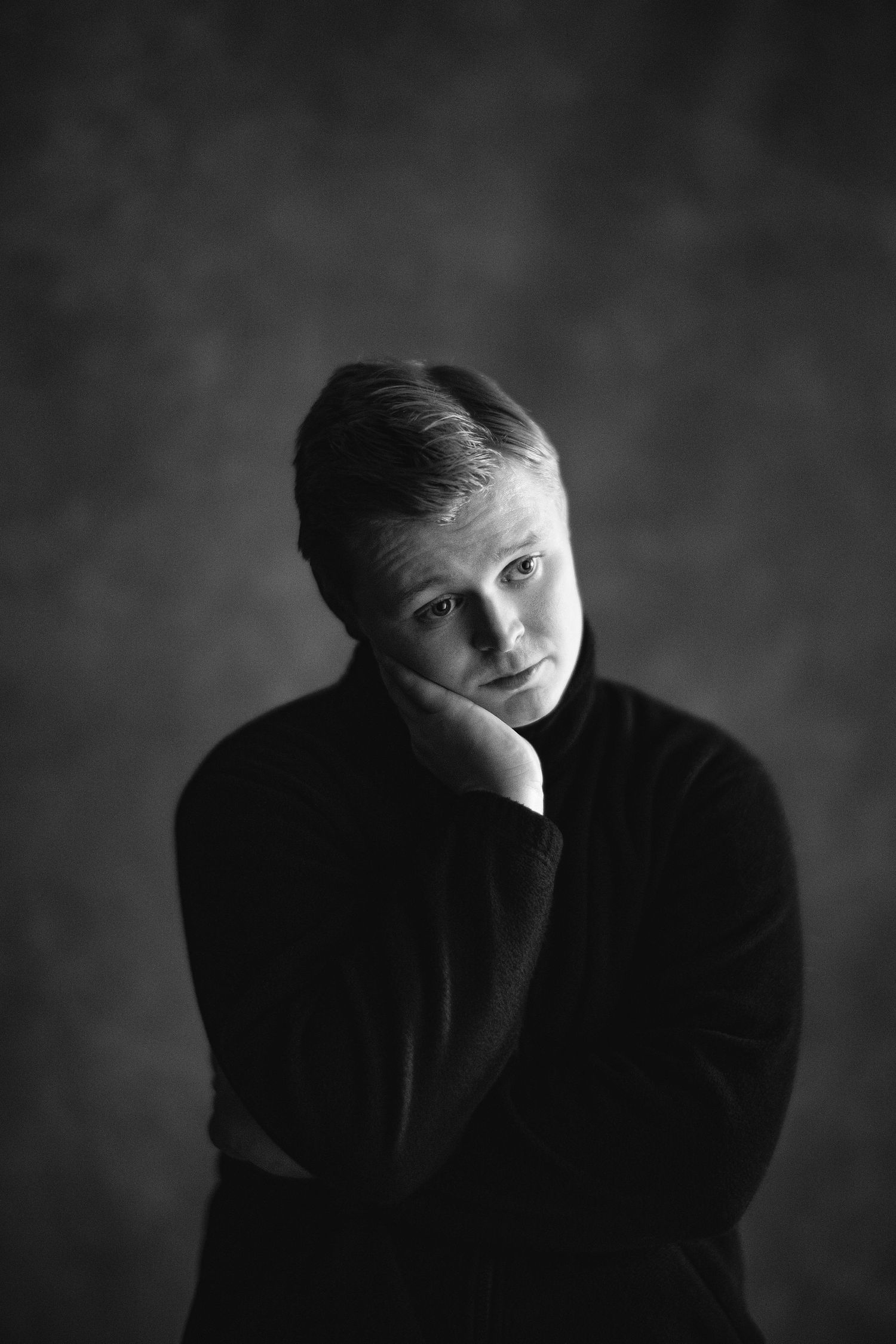 Dramatic black and white portrait series showing contemplative poses in dark lighting.