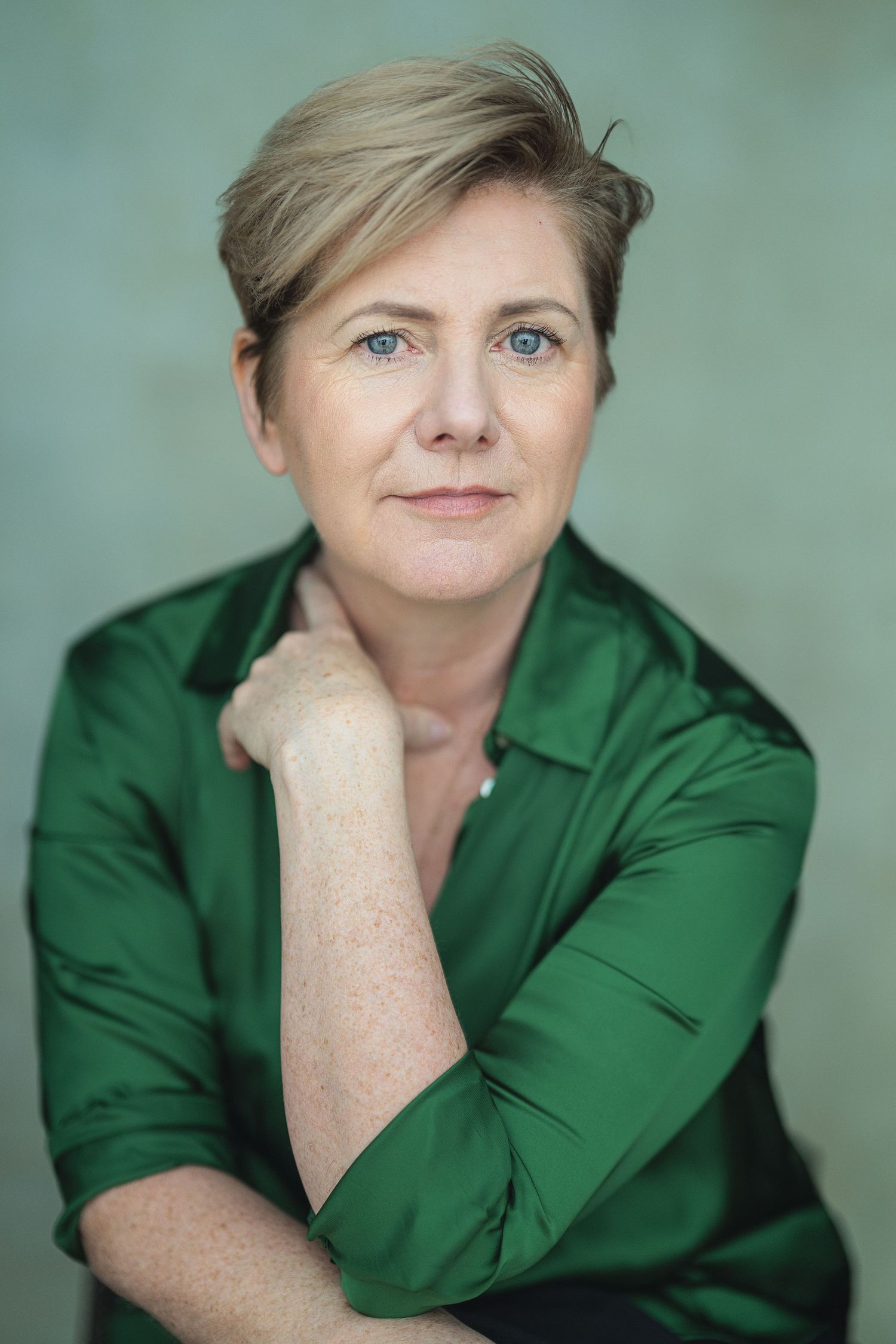 A series of professional headshots showing a person in a green blouse against a soft teal background.