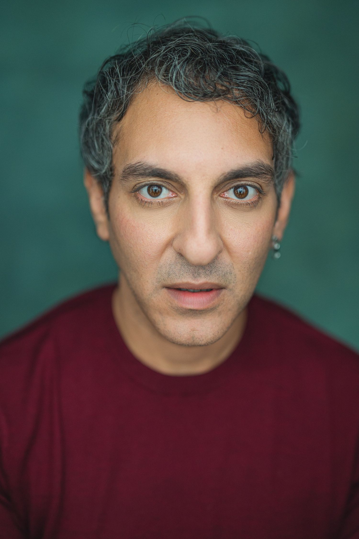 A series of headshots showing someone wearing a burgundy sweater against a teal background with changing expressions.