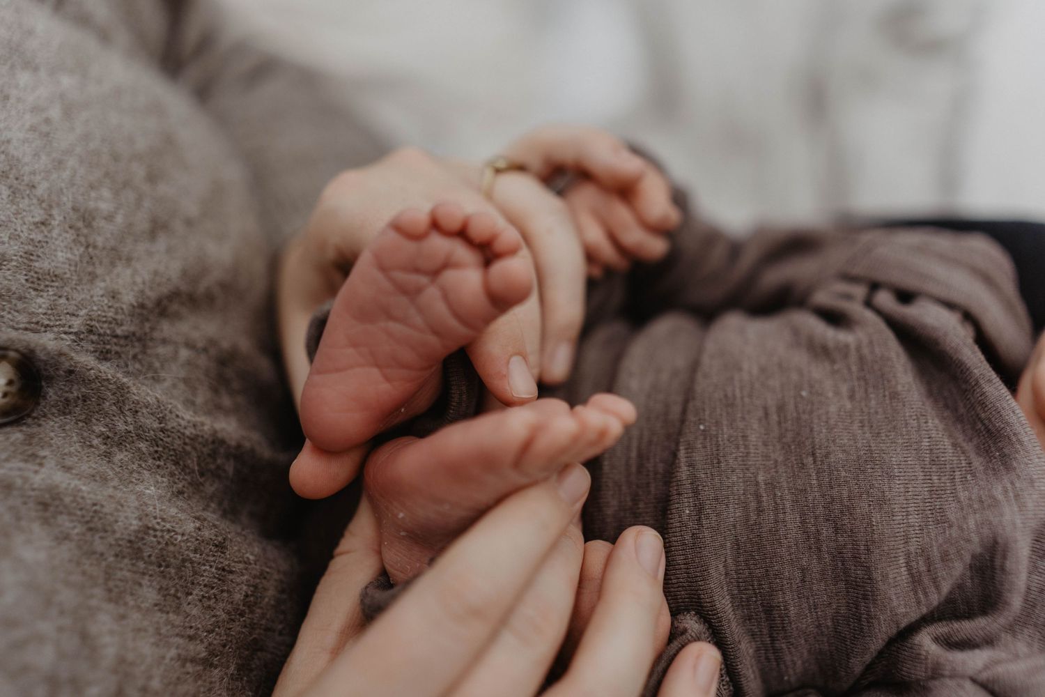 Close-up of tiny baby feet and hands being held gently.