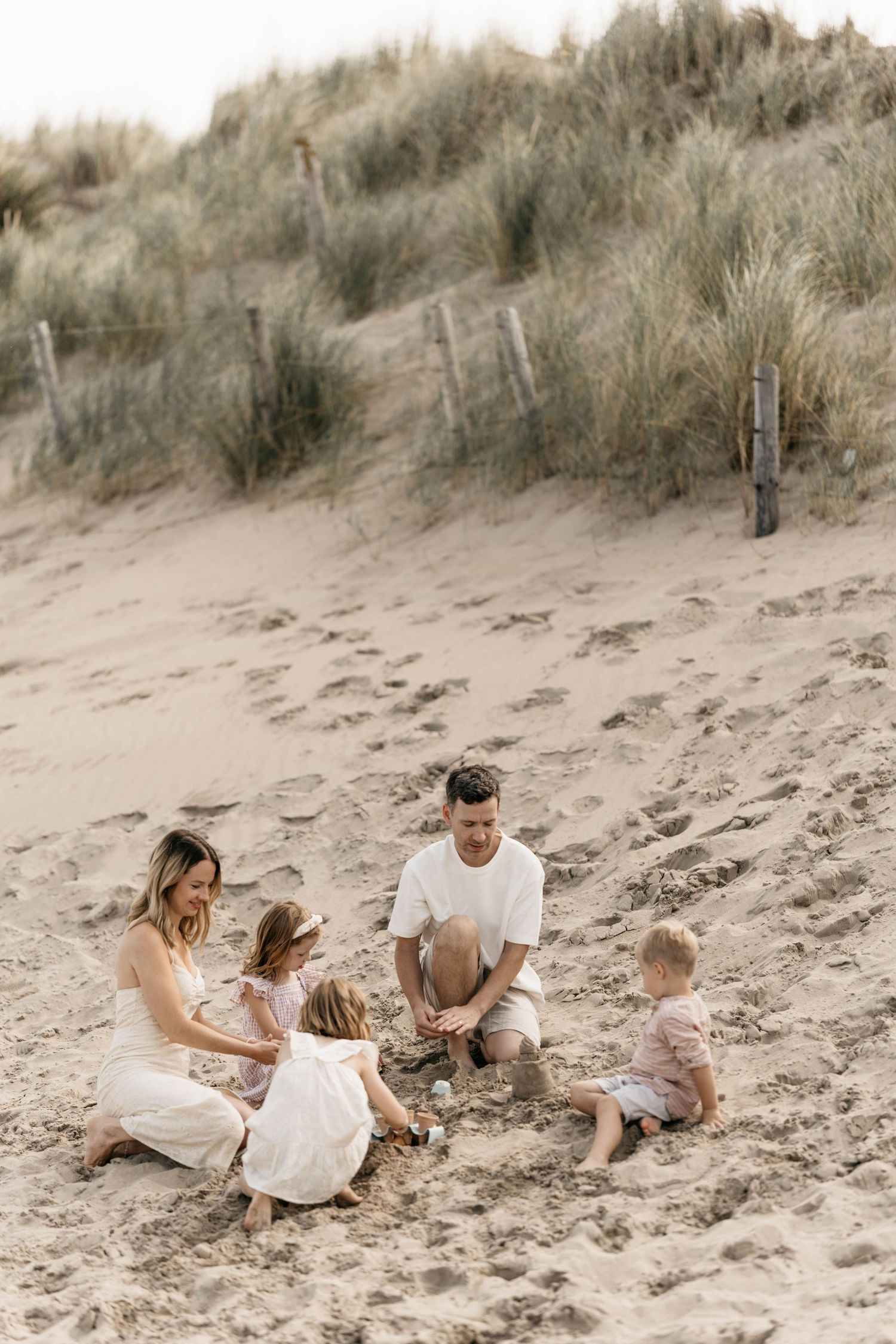 Family enjoying time together sitting on sand dunes at the beach.