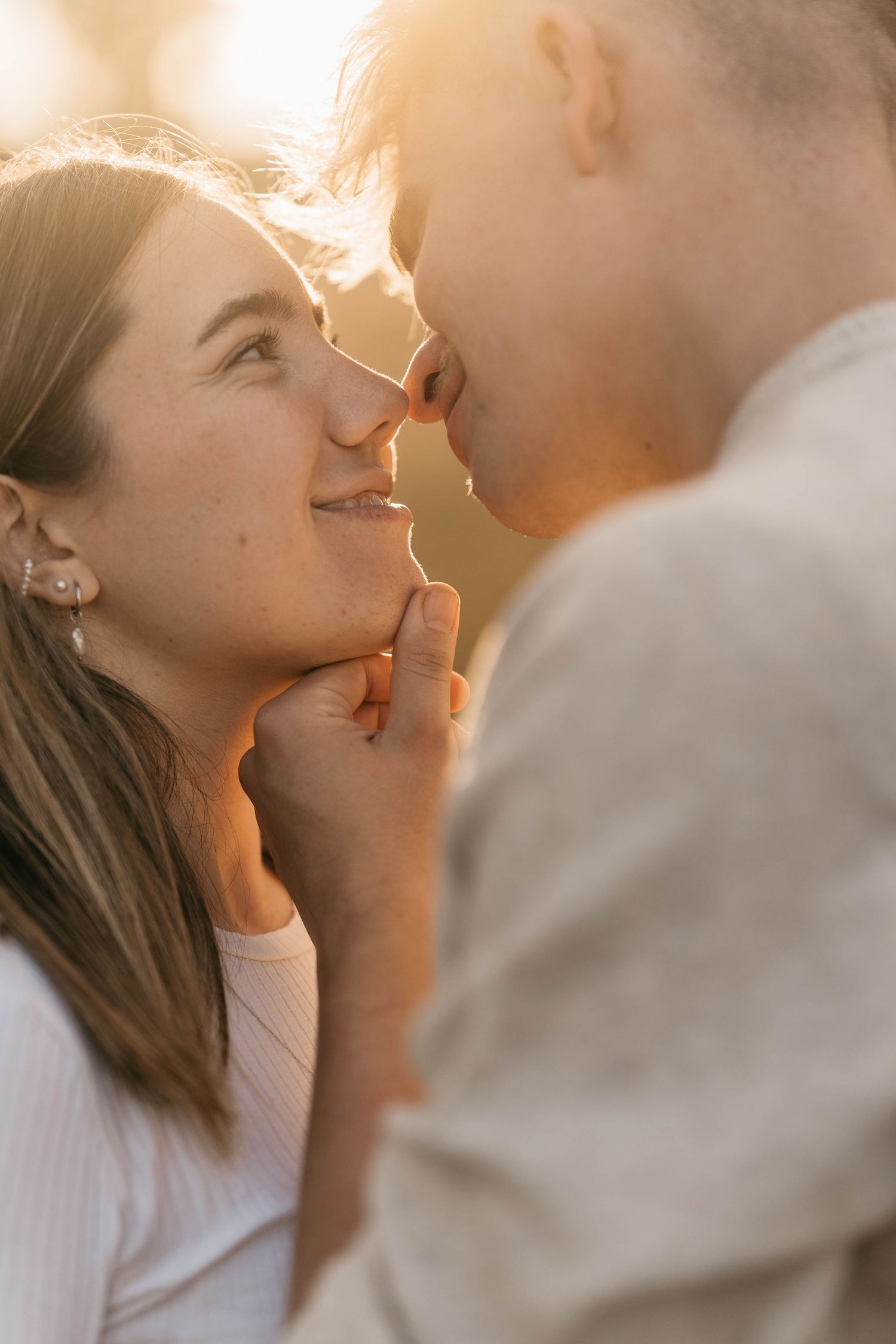 Intimate close-up of couple sharing tender moment in golden sunlight.