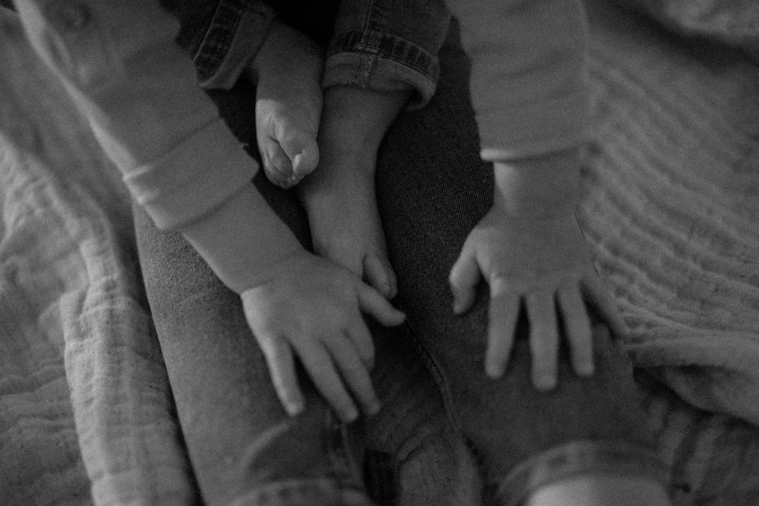 Black and white close-up of small hands resting on fabric.
