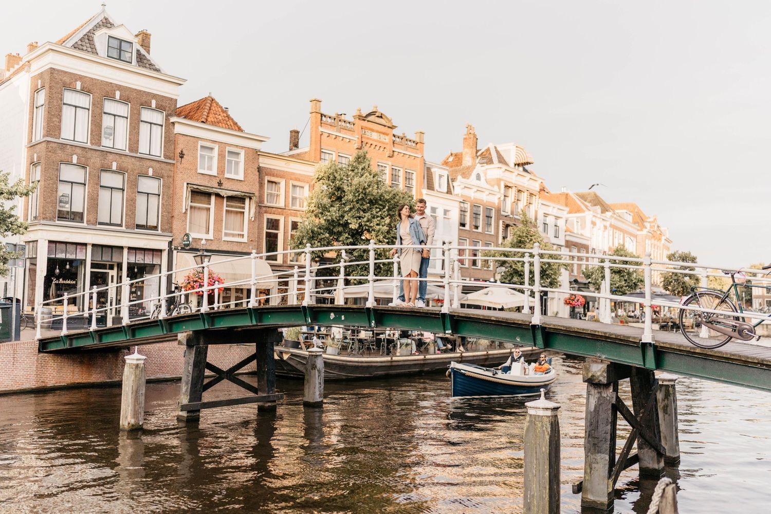 Historic Dutch canal with traditional architecture and bridge in warm evening light.
