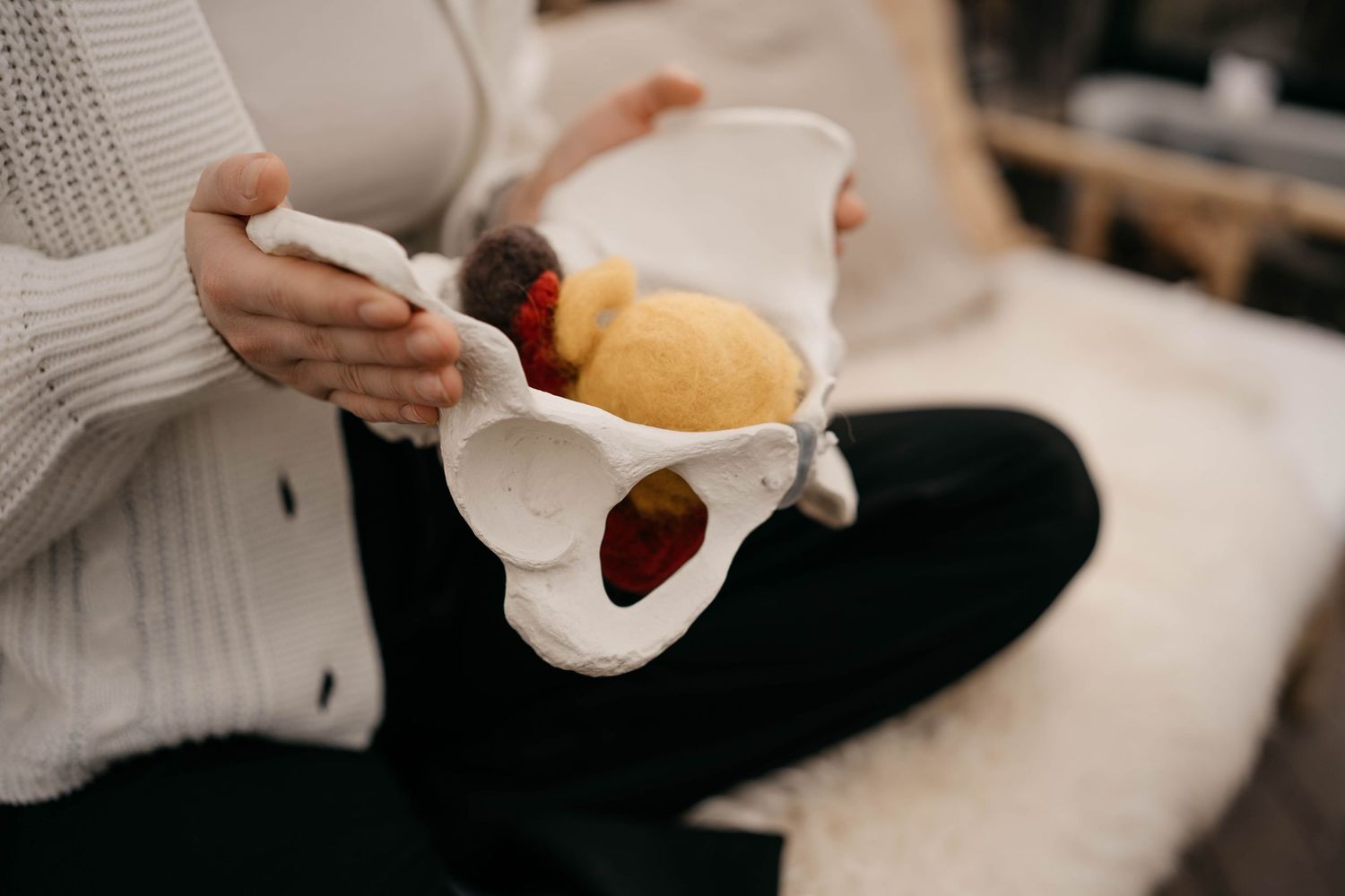 Person in cream sweater holding reusable mesh produce bags with fresh fruit and vegetables.