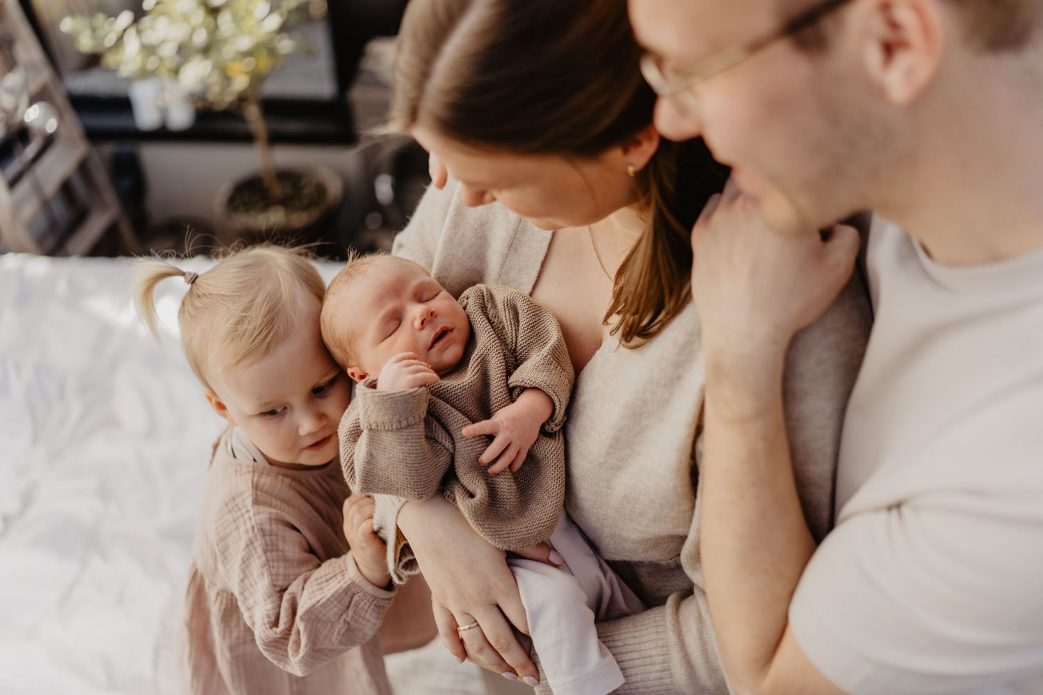 A young family shares an intimate moment together while relaxing on a white couch at home.
