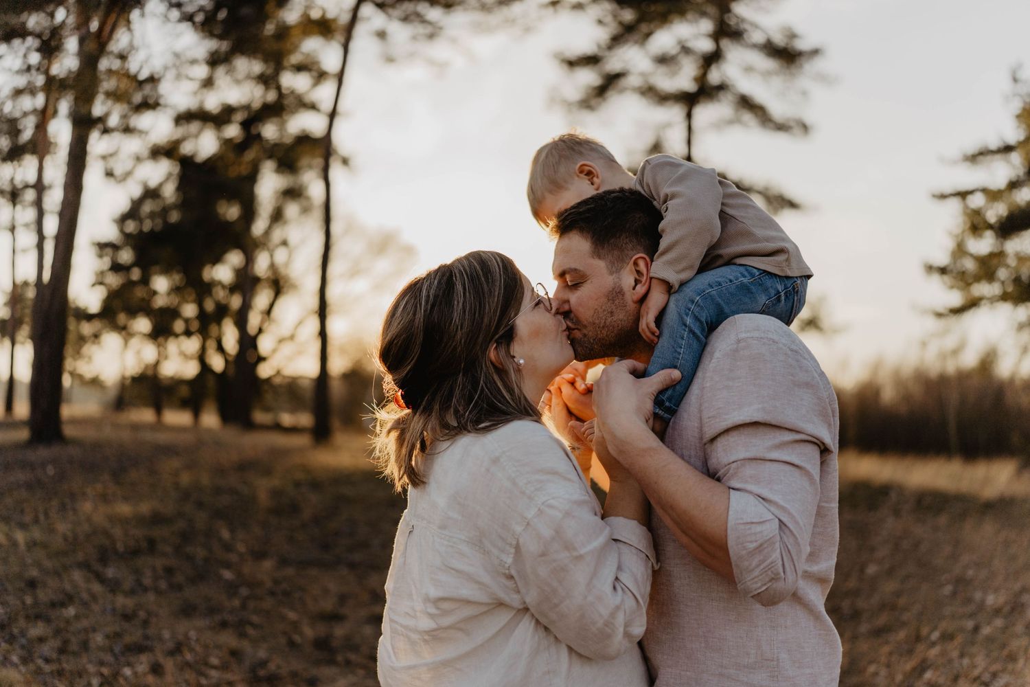 Intimate family embrace captured during golden hour in a forest setting.