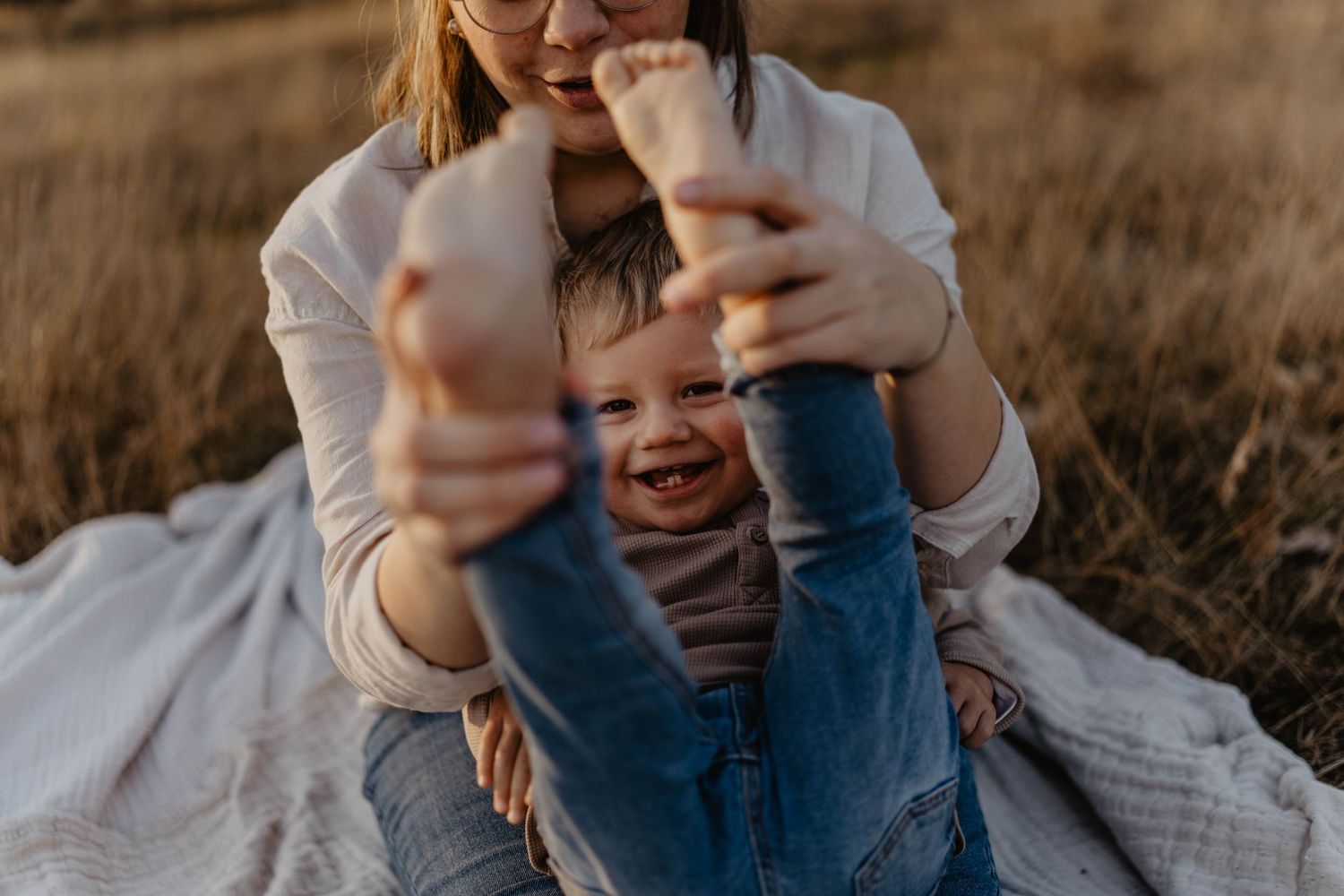 Playful moment captured in warm sunlight during outdoor family photoshoot.