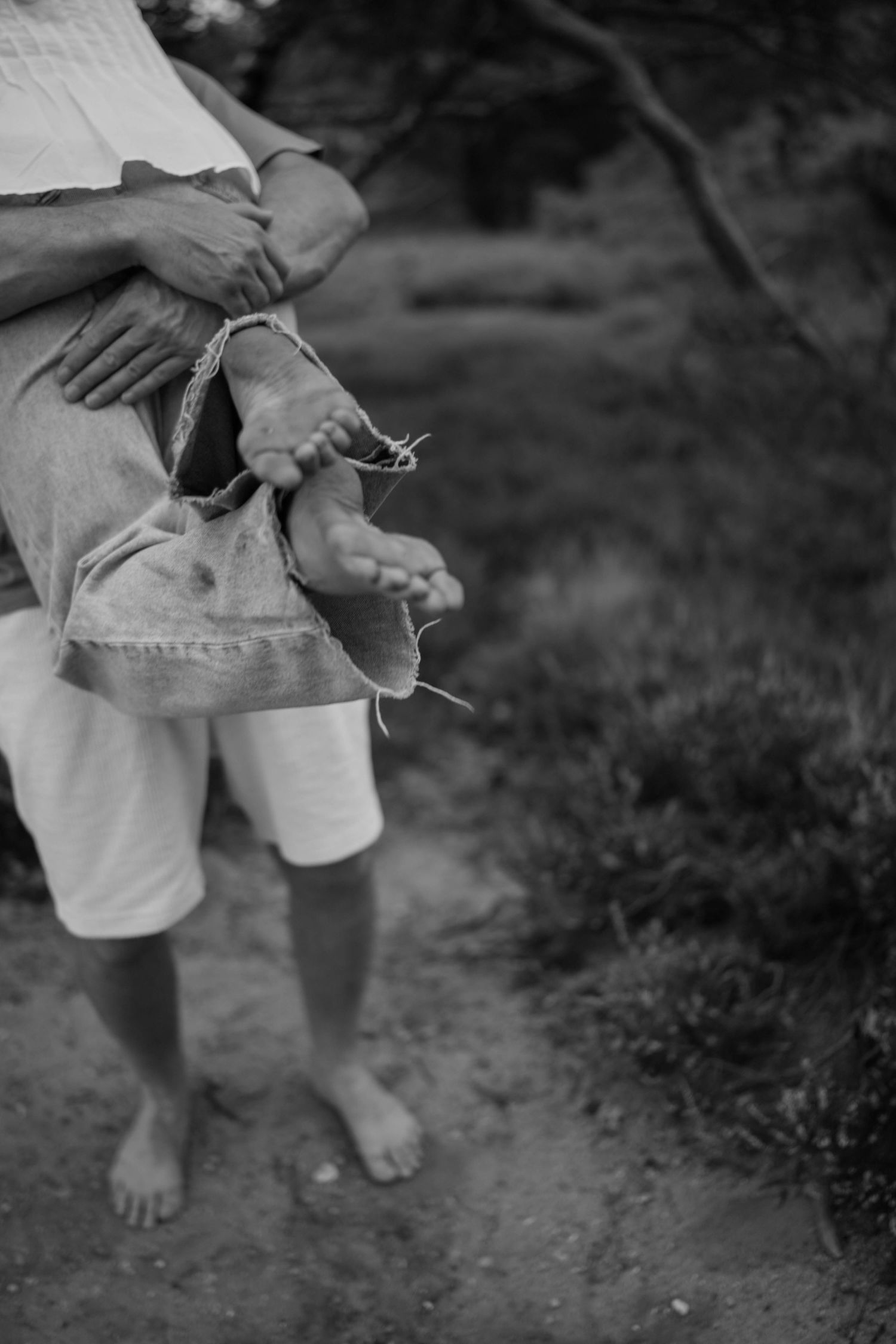 Black and white closeup of bare feet on dirt path showing casual intimate moment.