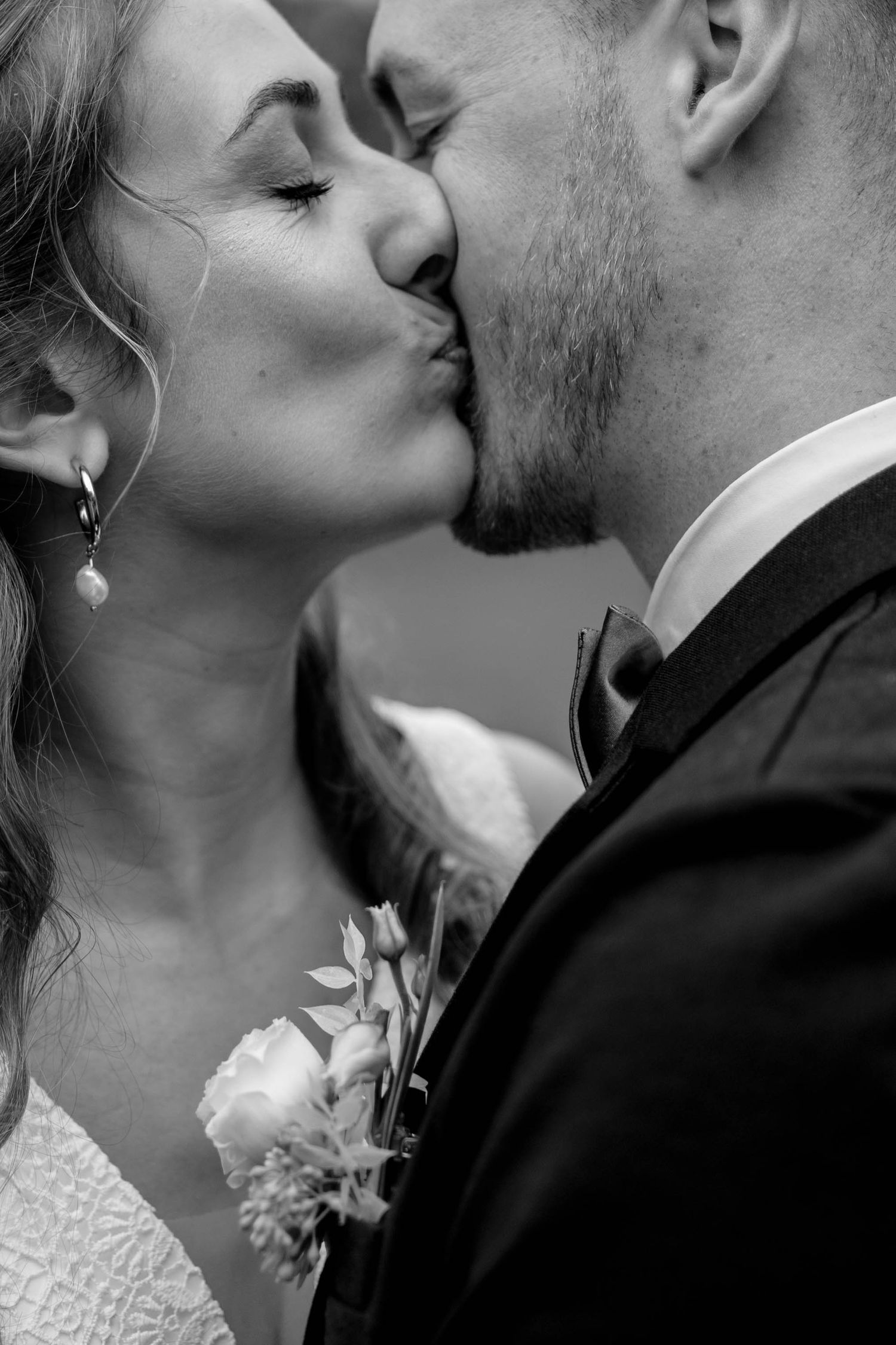 A romantic black and white wedding photography close-up of a tender kiss between newlyweds.