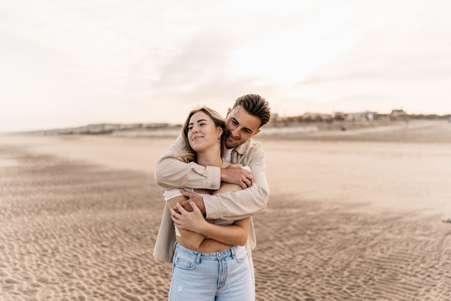 Romantic couple embracing on a sandy beach during sunset.