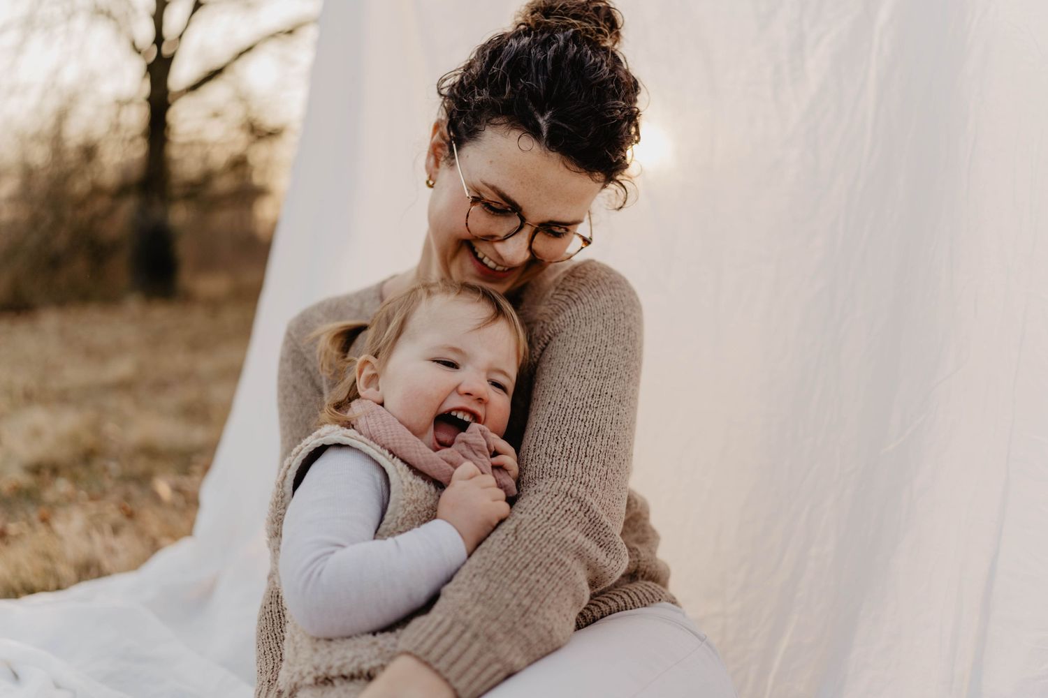 A tender moment shared between parent and child against a white backdrop at sunset.