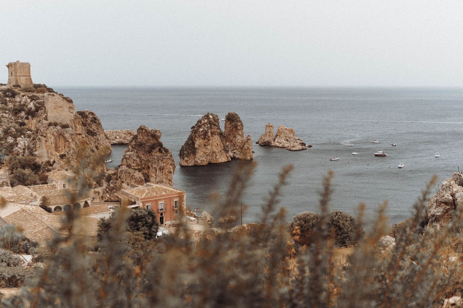 Rocky coastal landscape with large rock formations jutting out of the ocean against a misty seascape view.