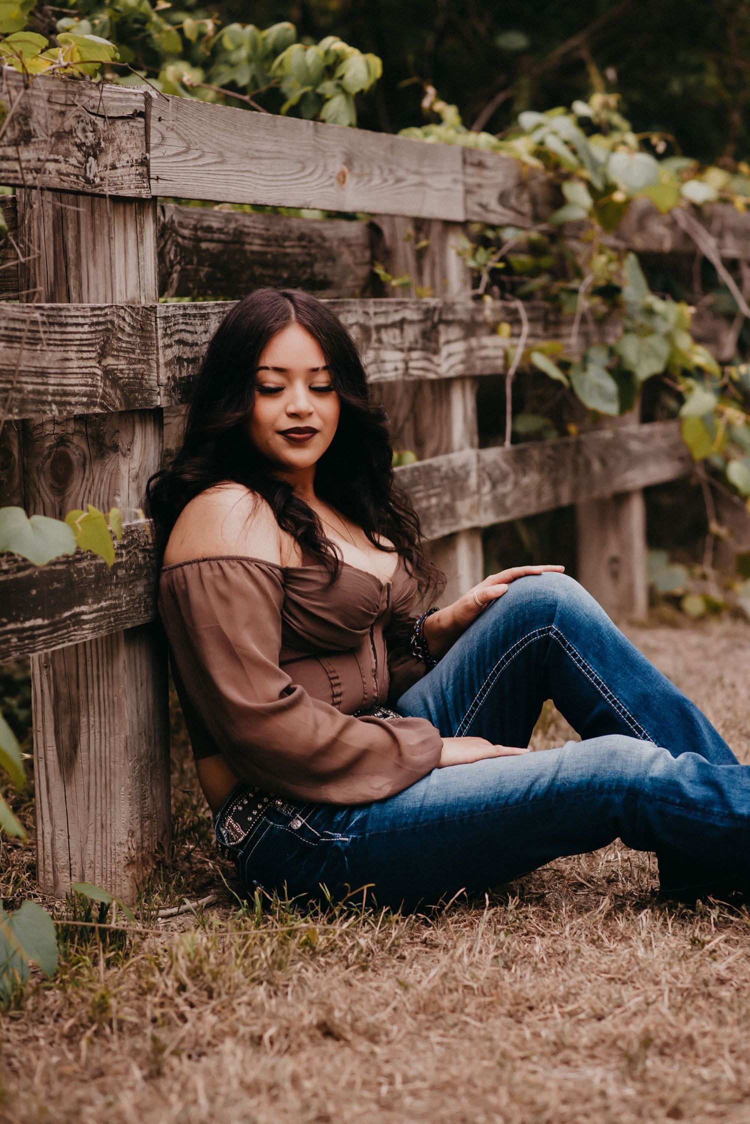Senior girl sitting against a fence