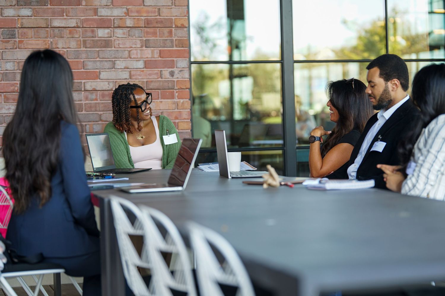 Diverse professionals networking at a modern conference table with laptops during a business meeting.